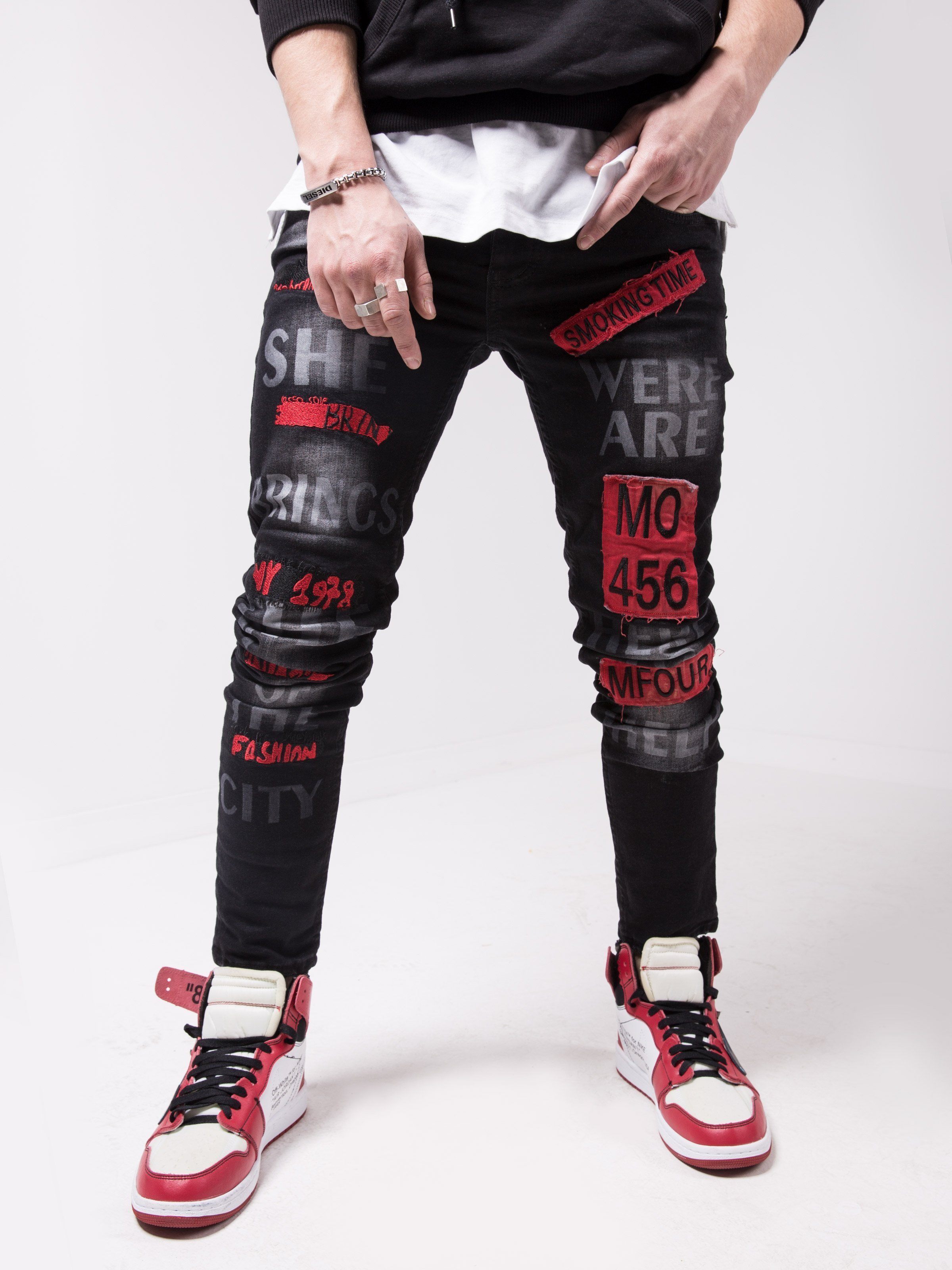 A man wearing a pair of GHETTO BIRD jeans with red and black stripes.