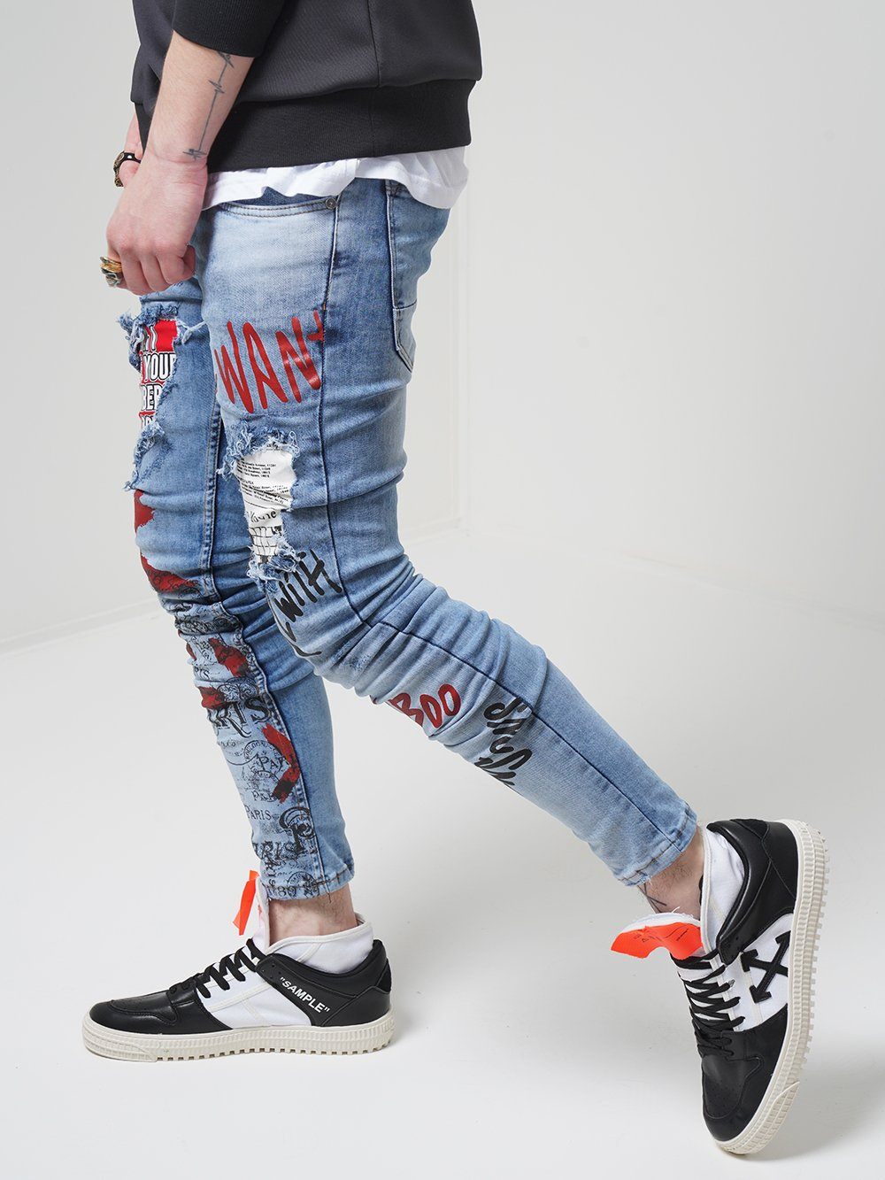 A man wearing a pair of BANKSY jeans and sneakers.