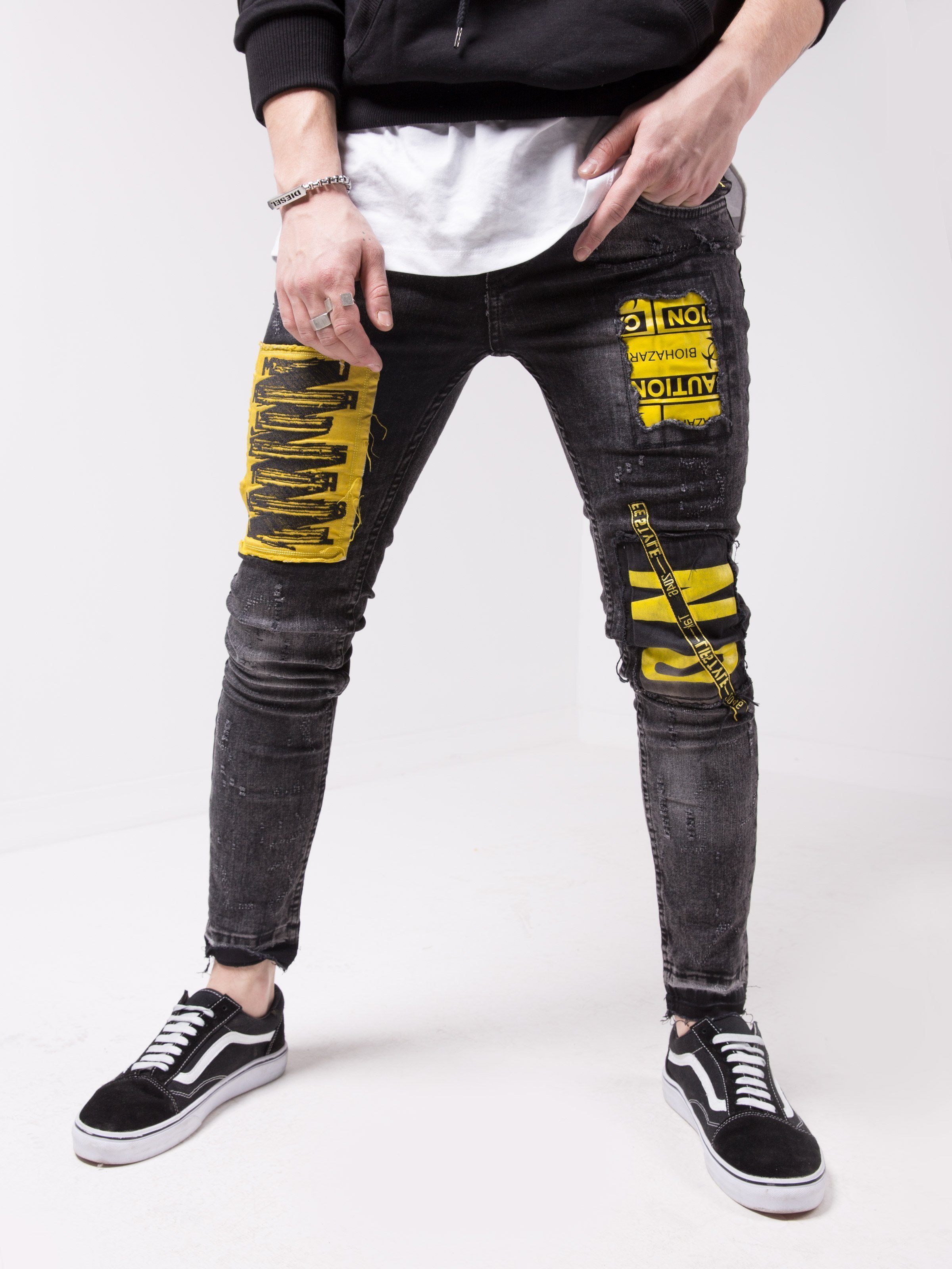 A man wearing a pair of MOUNT ONE jeans with yellow tape on them.