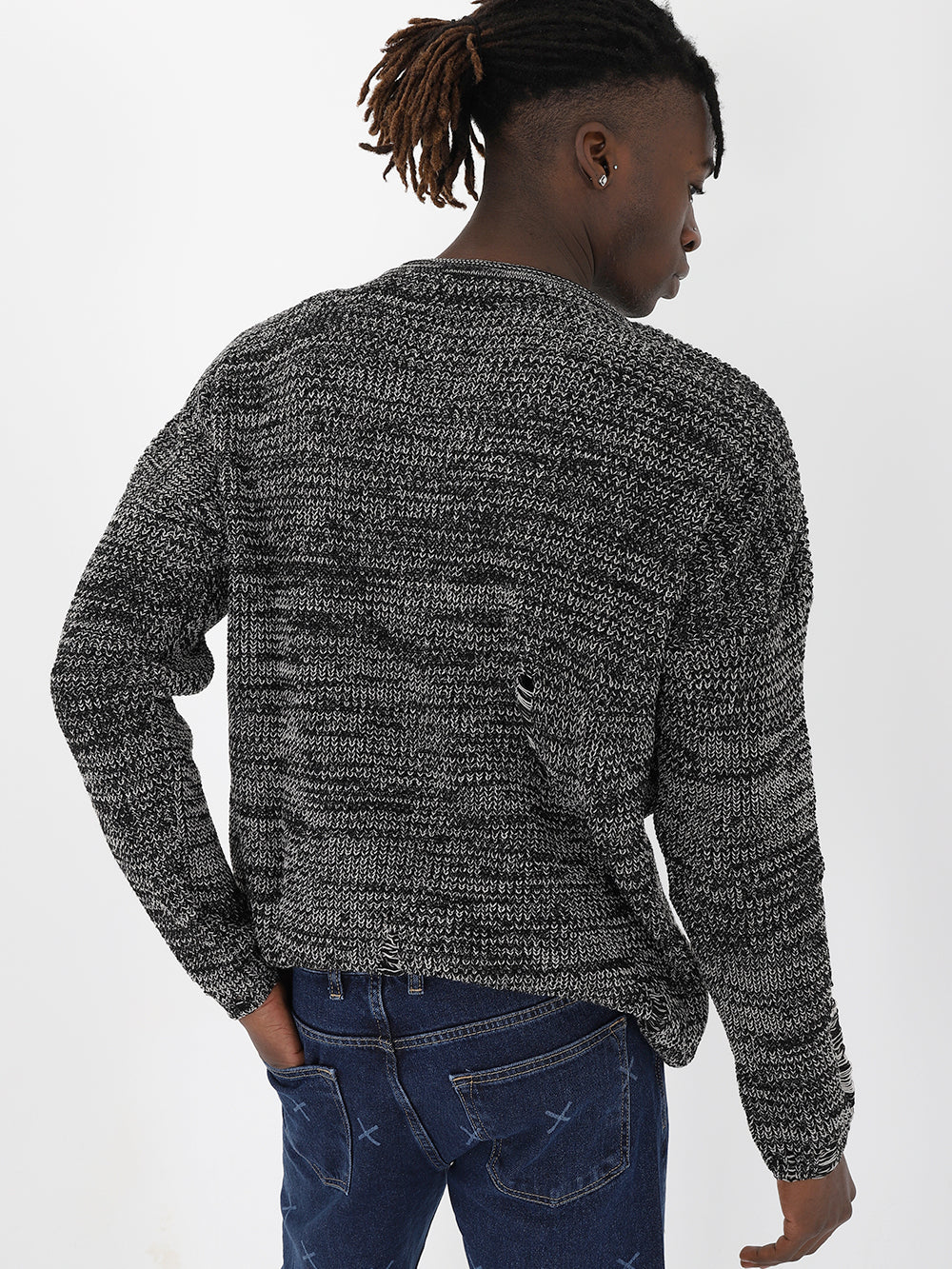 A man wearing a DISTRESSED GENTLEMAN SWEATER | GRAY and jeans with a true-to-size fit.
