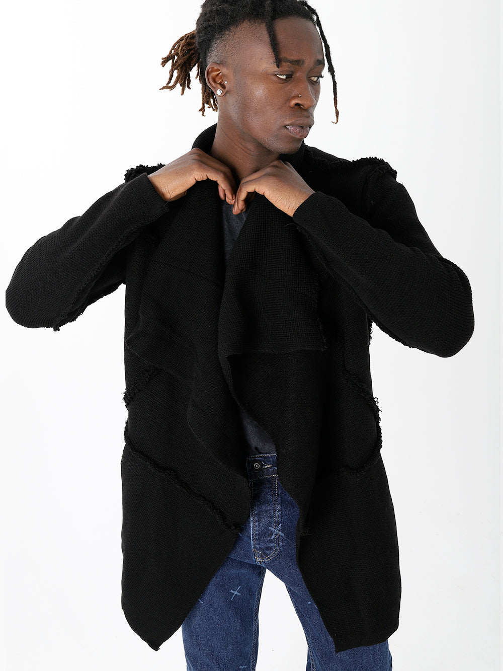 A man with dreadlocks wearing a HOODED DISTRESSED CARDIGAN // BLACK and skinny fit jeans.