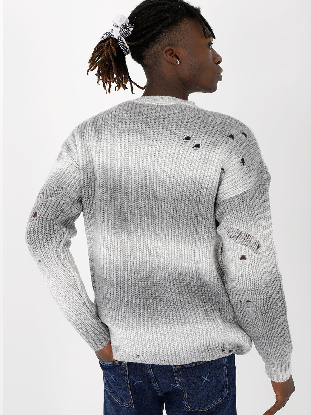 The back view of a man wearing a DISTRESSED GENTLEMAN SWEATER | WHITE-GRAY with holes.