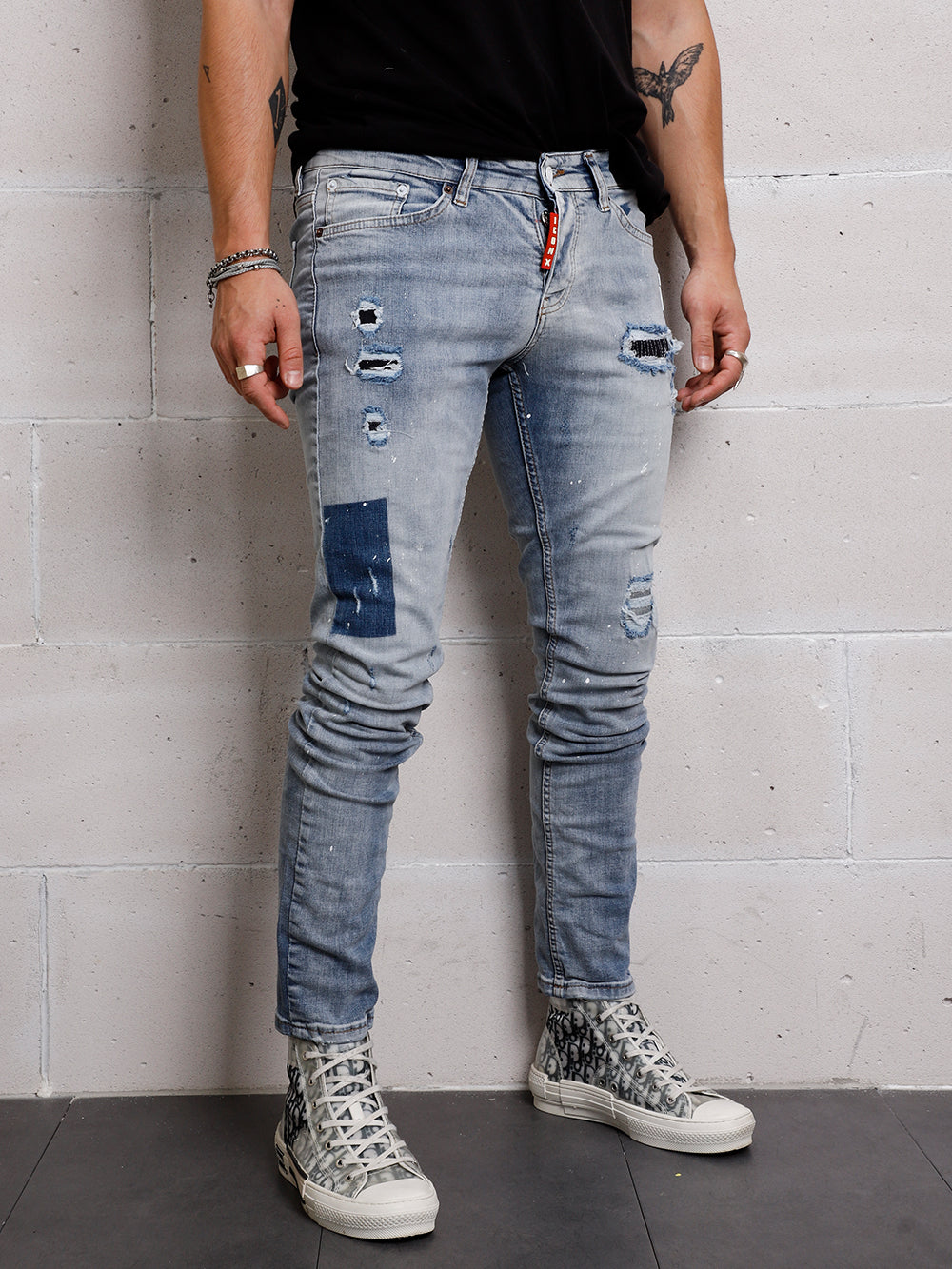 A man in a slim fit t-shirt and SKY BLUE ICON DENIM jeans standing against a distressed wall.