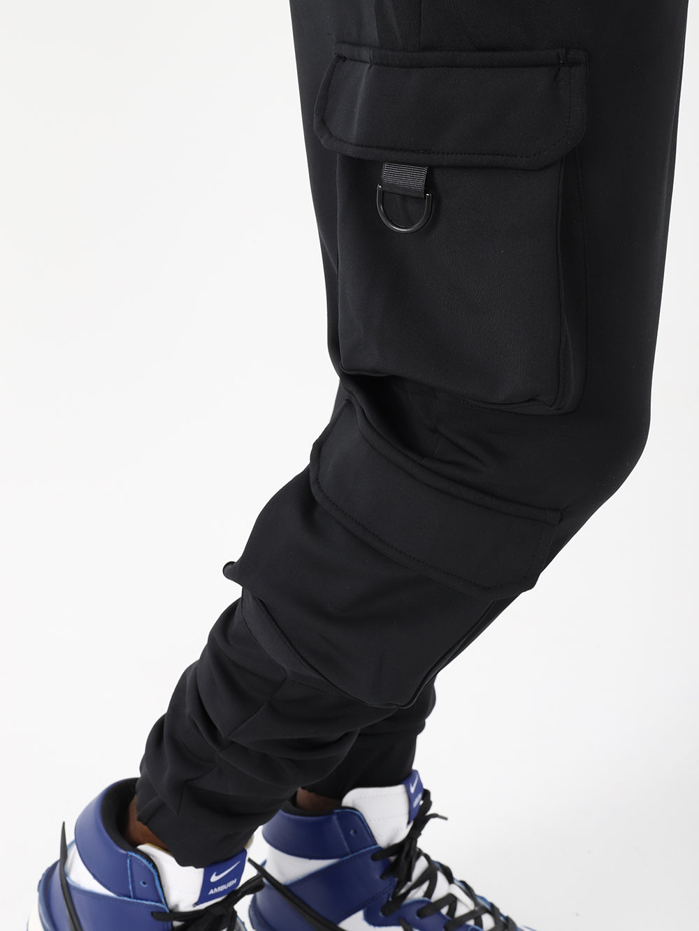 A man wearing black VENTURA joggers with adjustable ankle cuffs and blue sneakers.