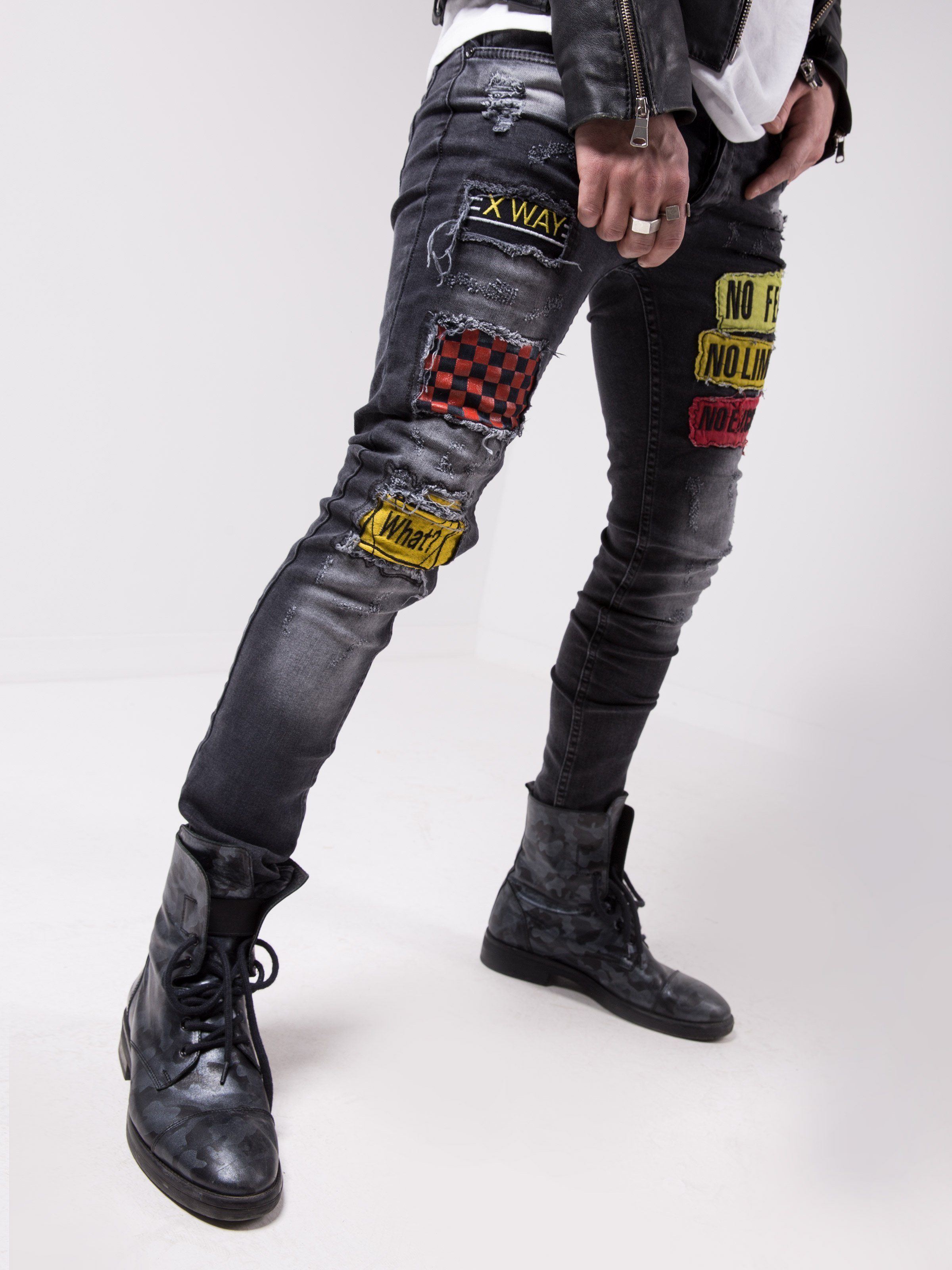 A man wearing a pair of FEARLESS jeans with patches on them that have a smooth feel.