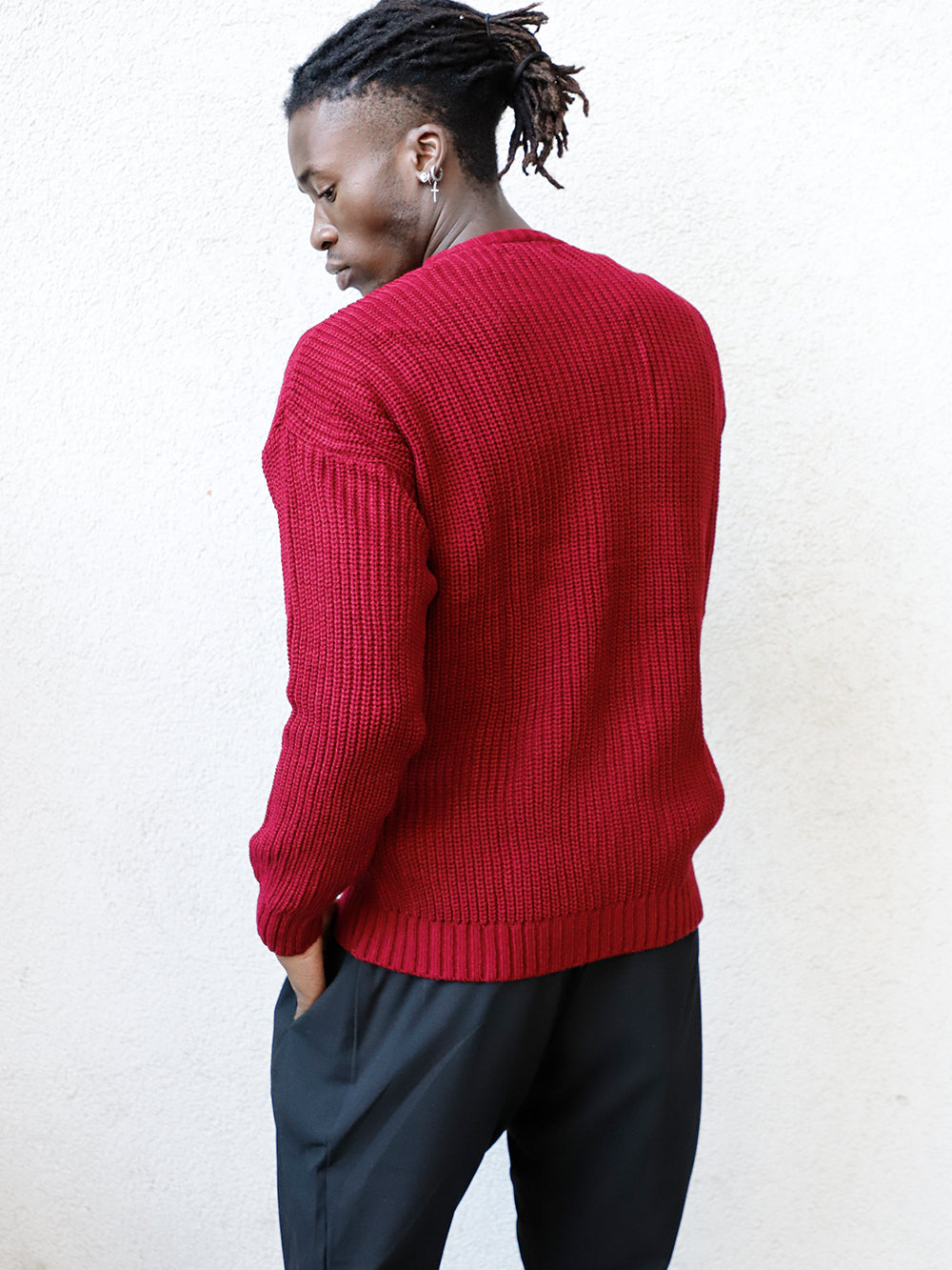 A man wearing the DISTRESSED GENTLEMAN SWEATER | BURGUNDY and black pants.