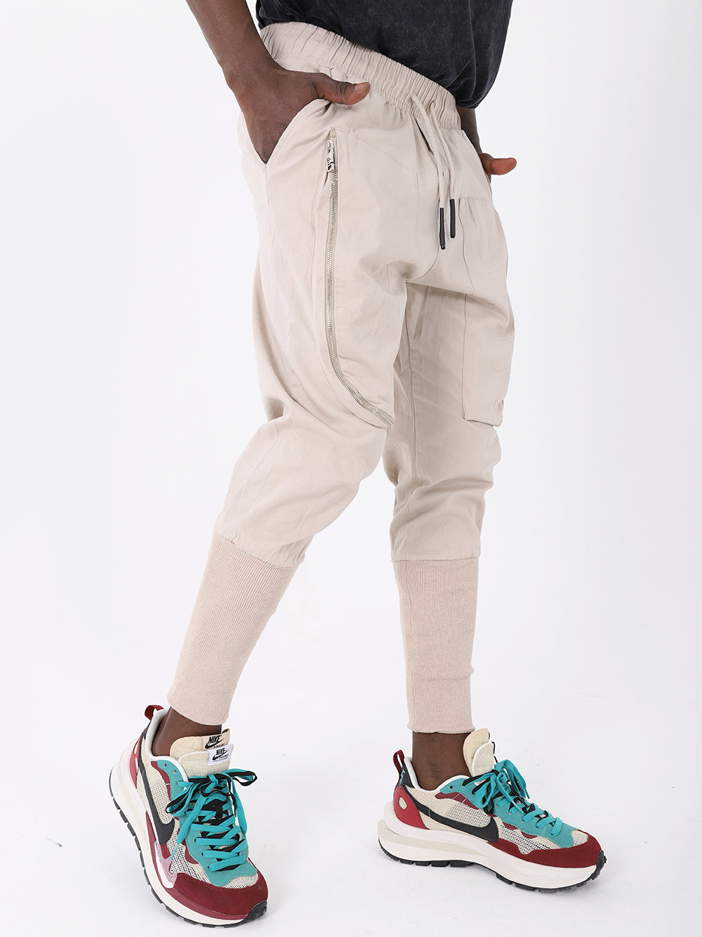 A man wearing ALTIS JOGGERS, a fashion item that features a beige color, adjustable drawstring waist, and paired with sneakers.