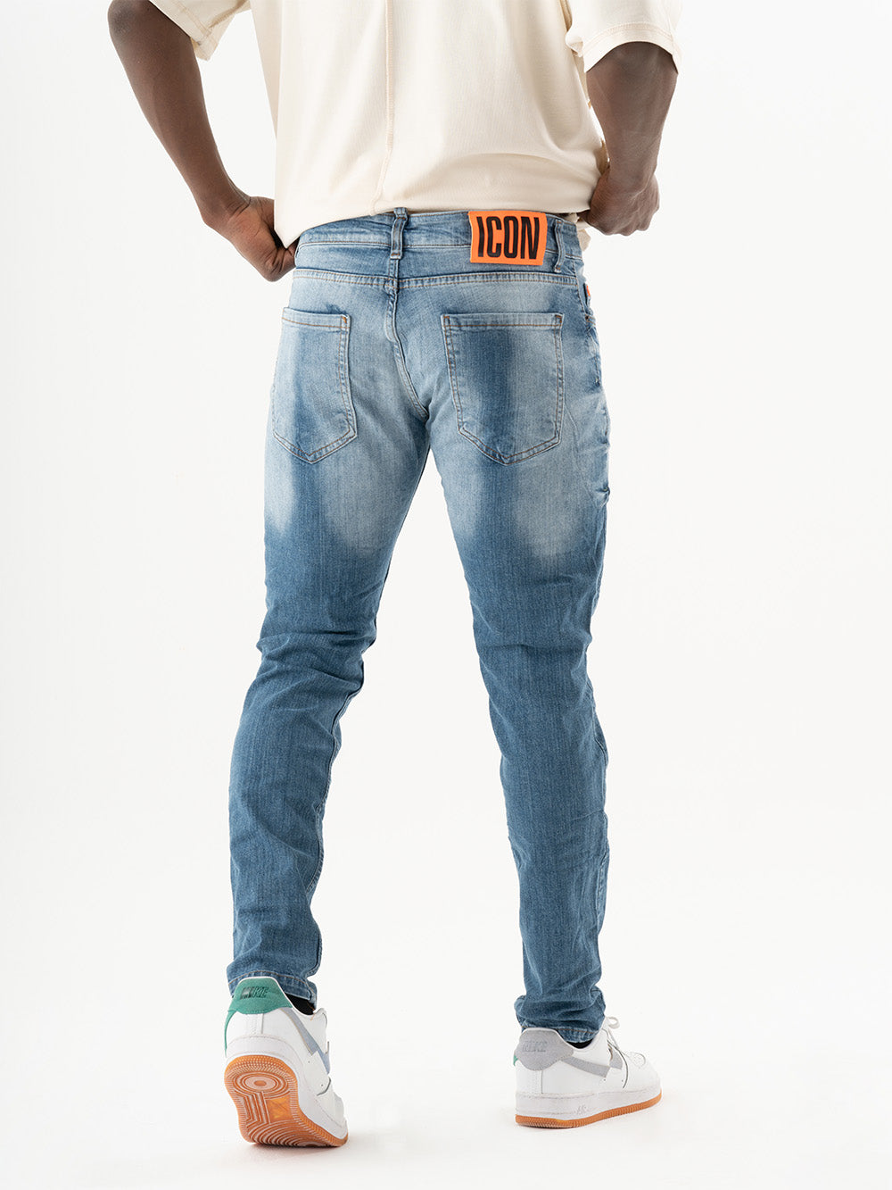 The back of a man wearing TEZAR jeans and a white t-shirt.
