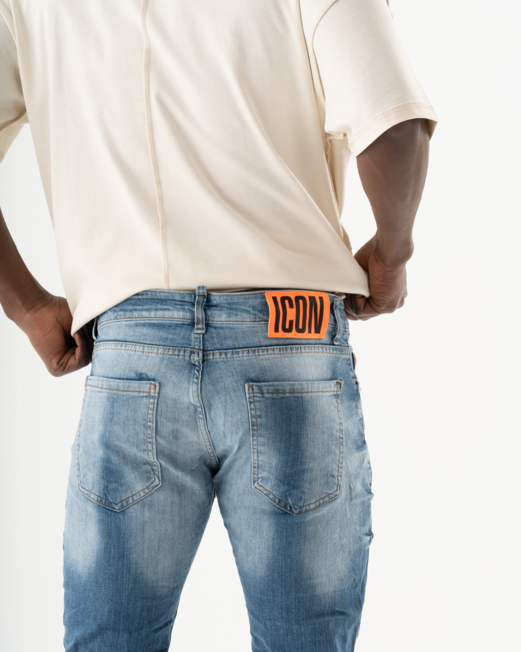 A man wearing a pair of ripped TEZAR jeans with an orange tag on the back.