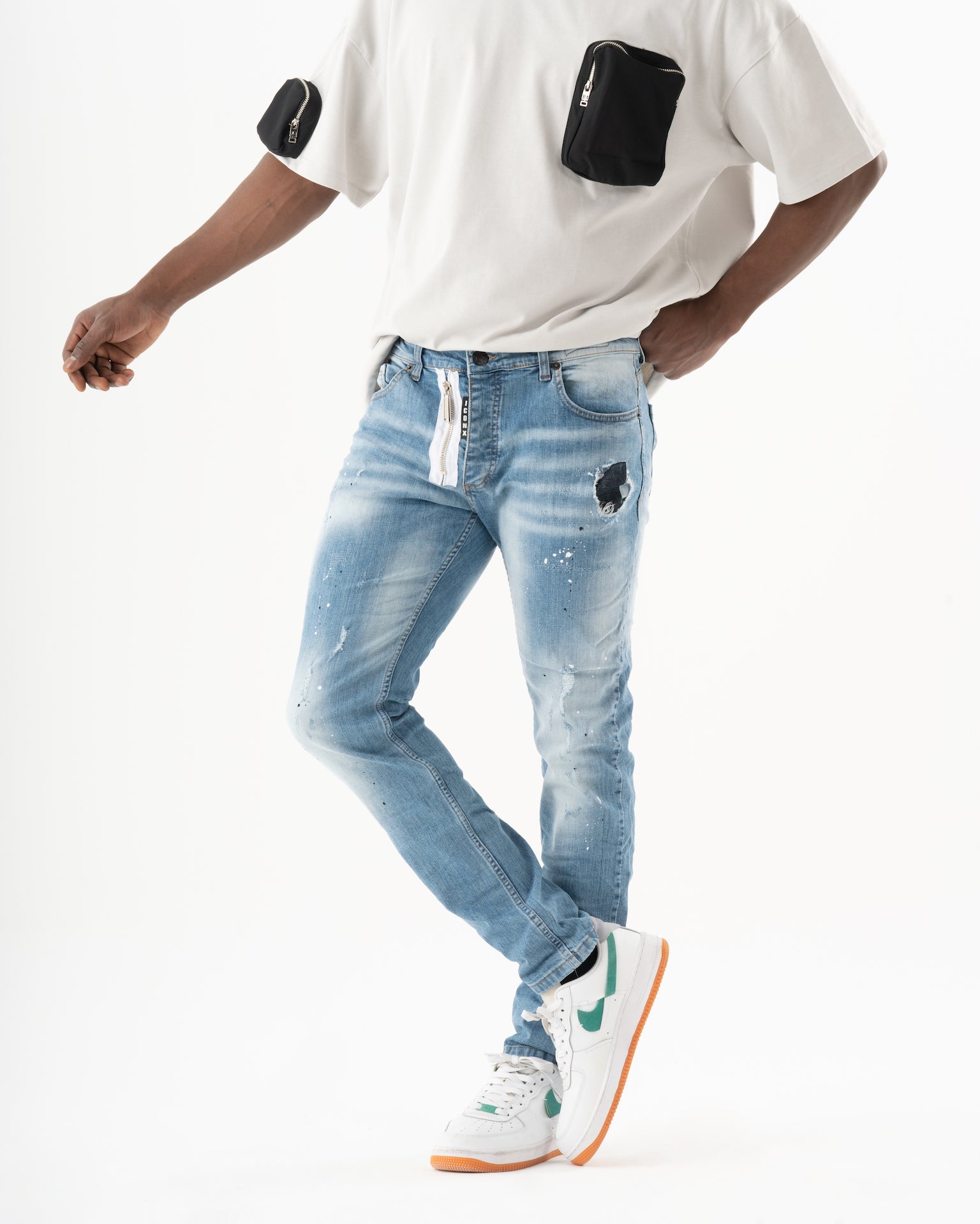 A man wearing a SKATER t - shirt and blue jeans.