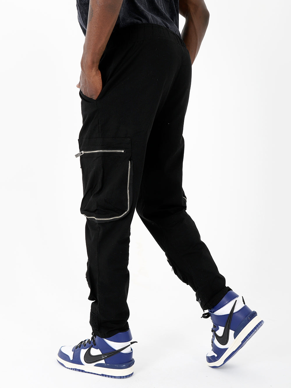 A man wearing black raider joggers and sneakers.