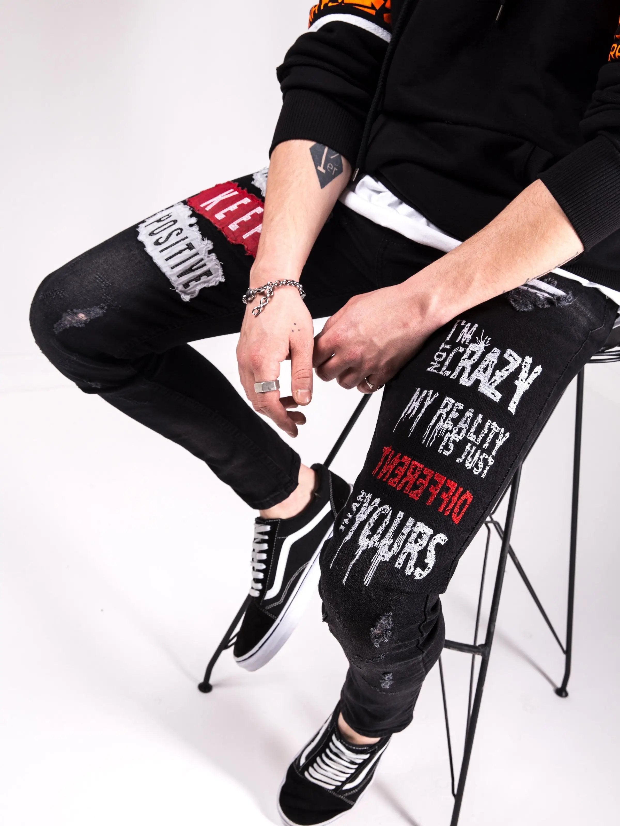 A man is sitting on a chair wearing I'M NOT CRAZY skinny fit jeans.