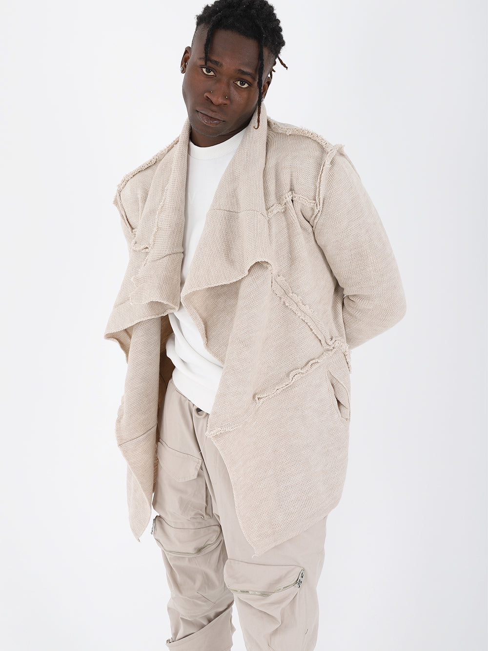 A black man wearing an ASYMMETRIC SHORT CARDIGAN // IVORY jacket and pants with a true to size fit.