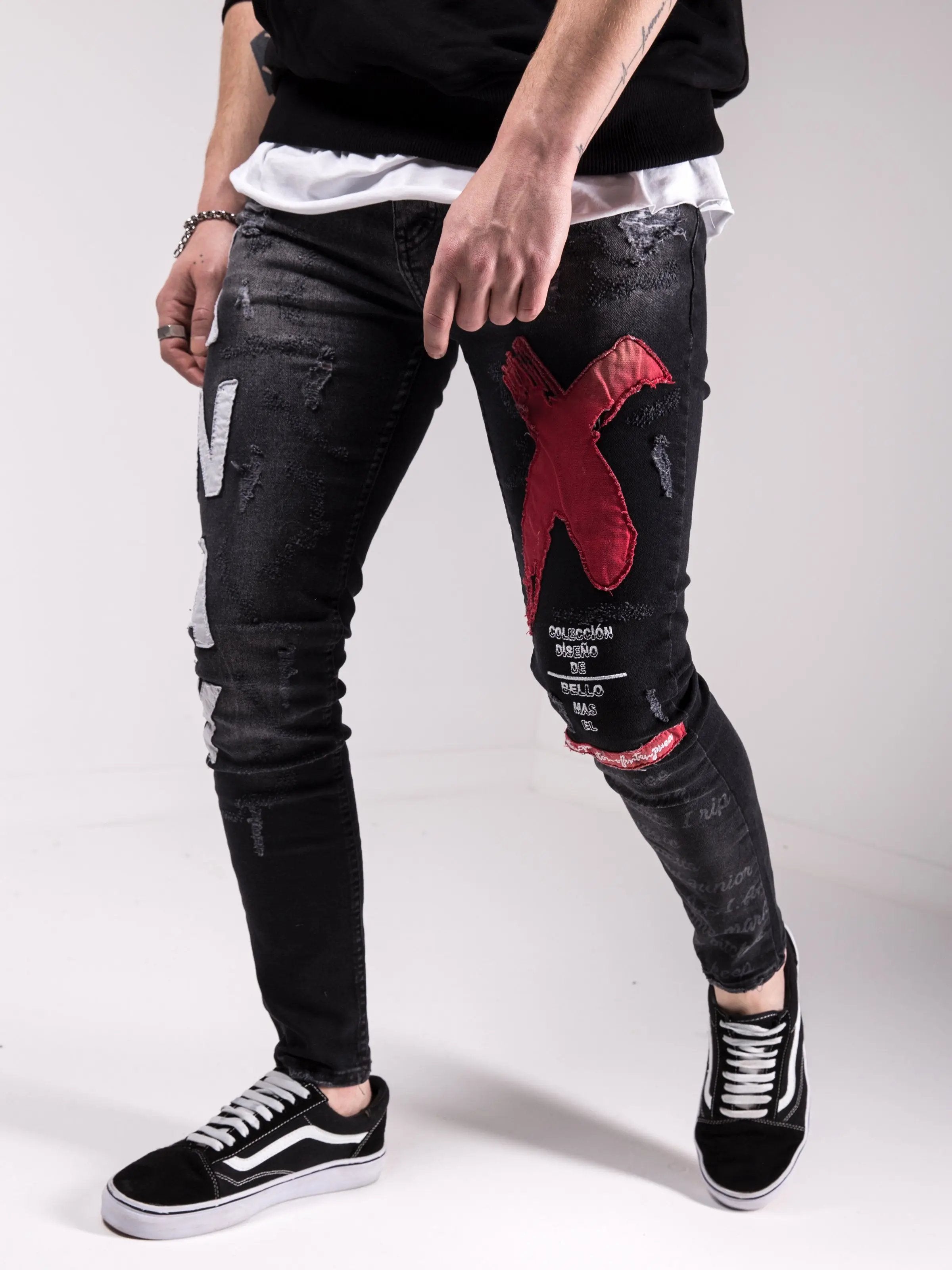 A man wearing MAD DOG skinny fit black and red ripped jeans.