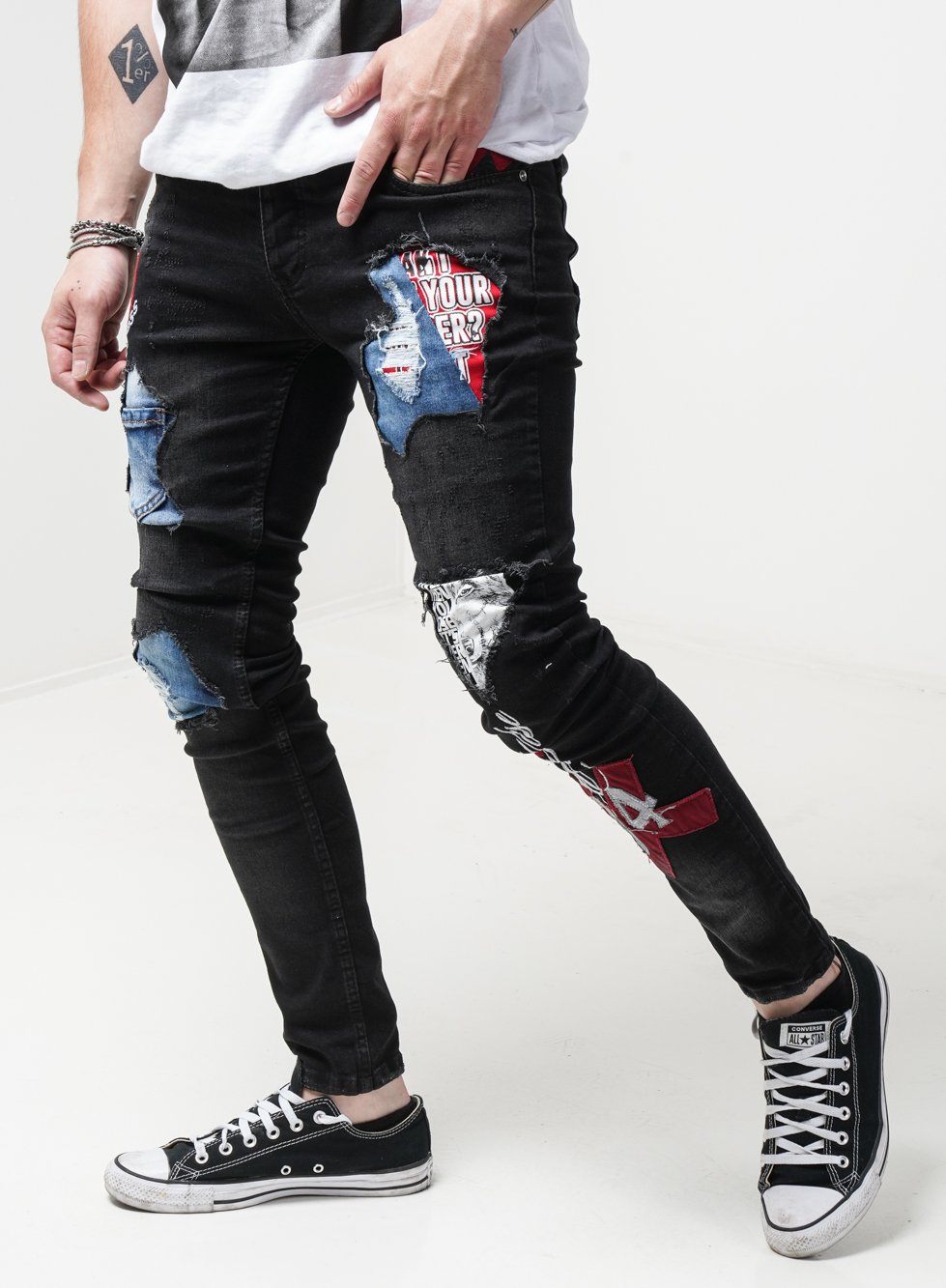 A man sporting stylish, ripped INSIDER skinny jeans and sneakers.