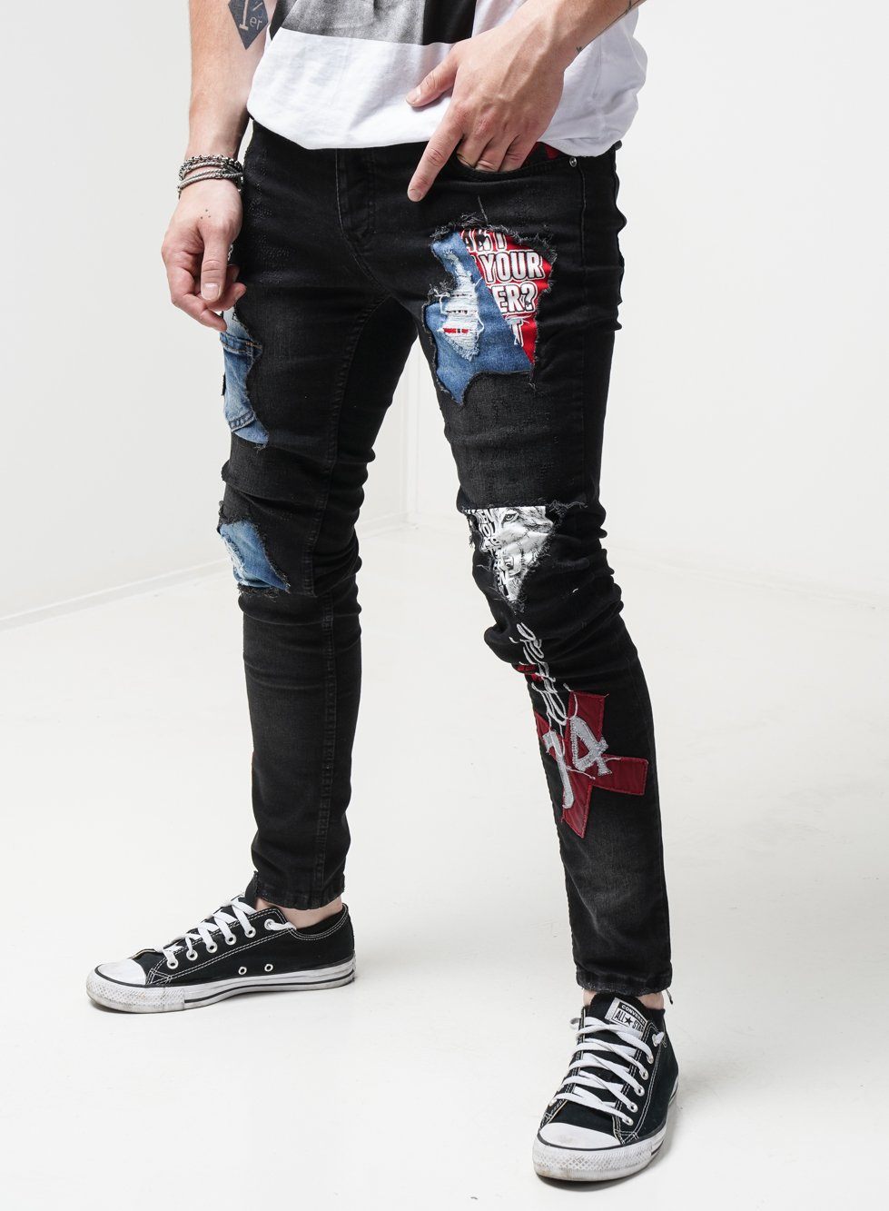 A man wearing a pair of INSIDER jeans with patches, showcasing mens streetwear.