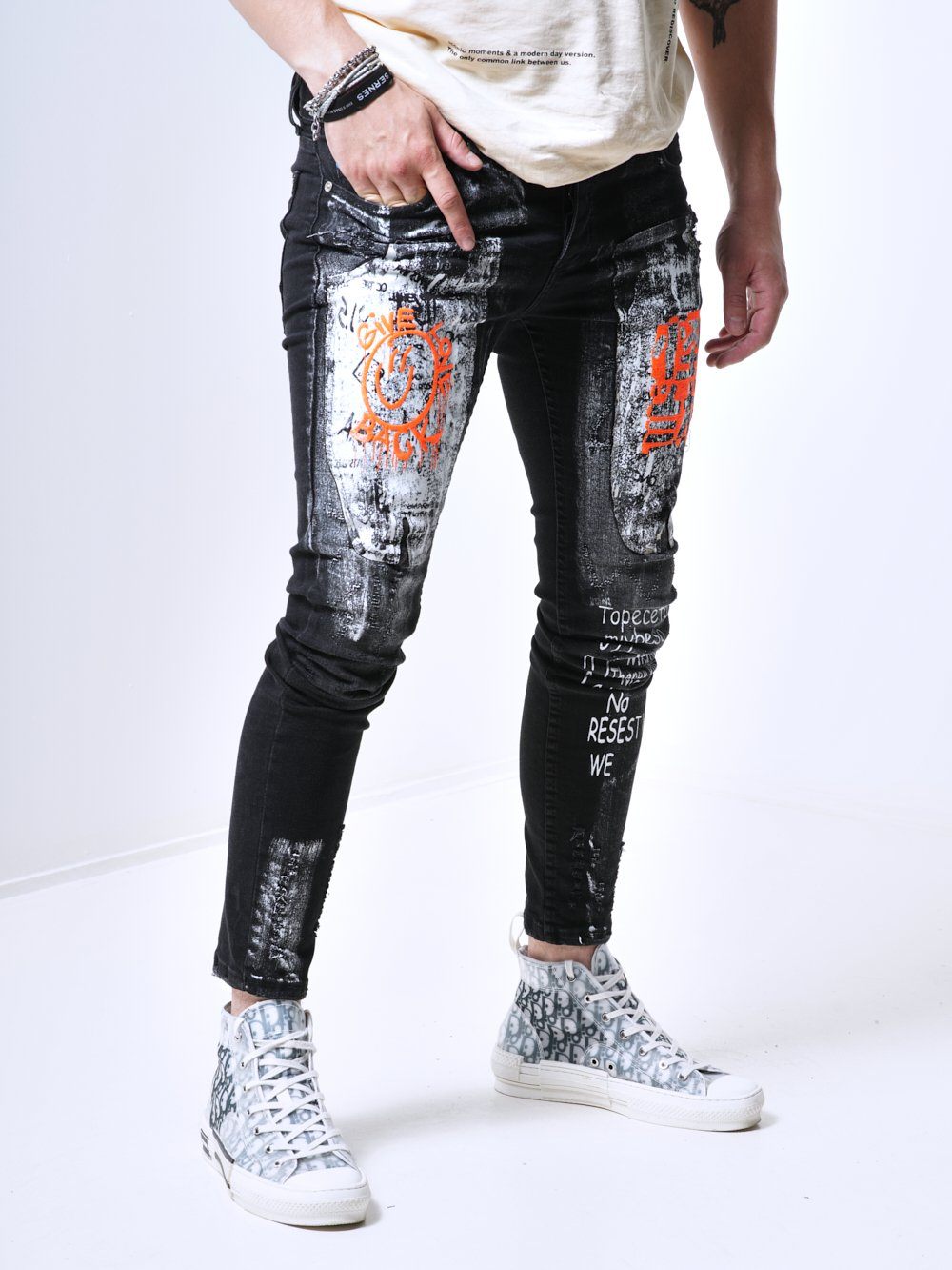 A man wearing a pair of SIXTY SIX jeans with graffiti on them.