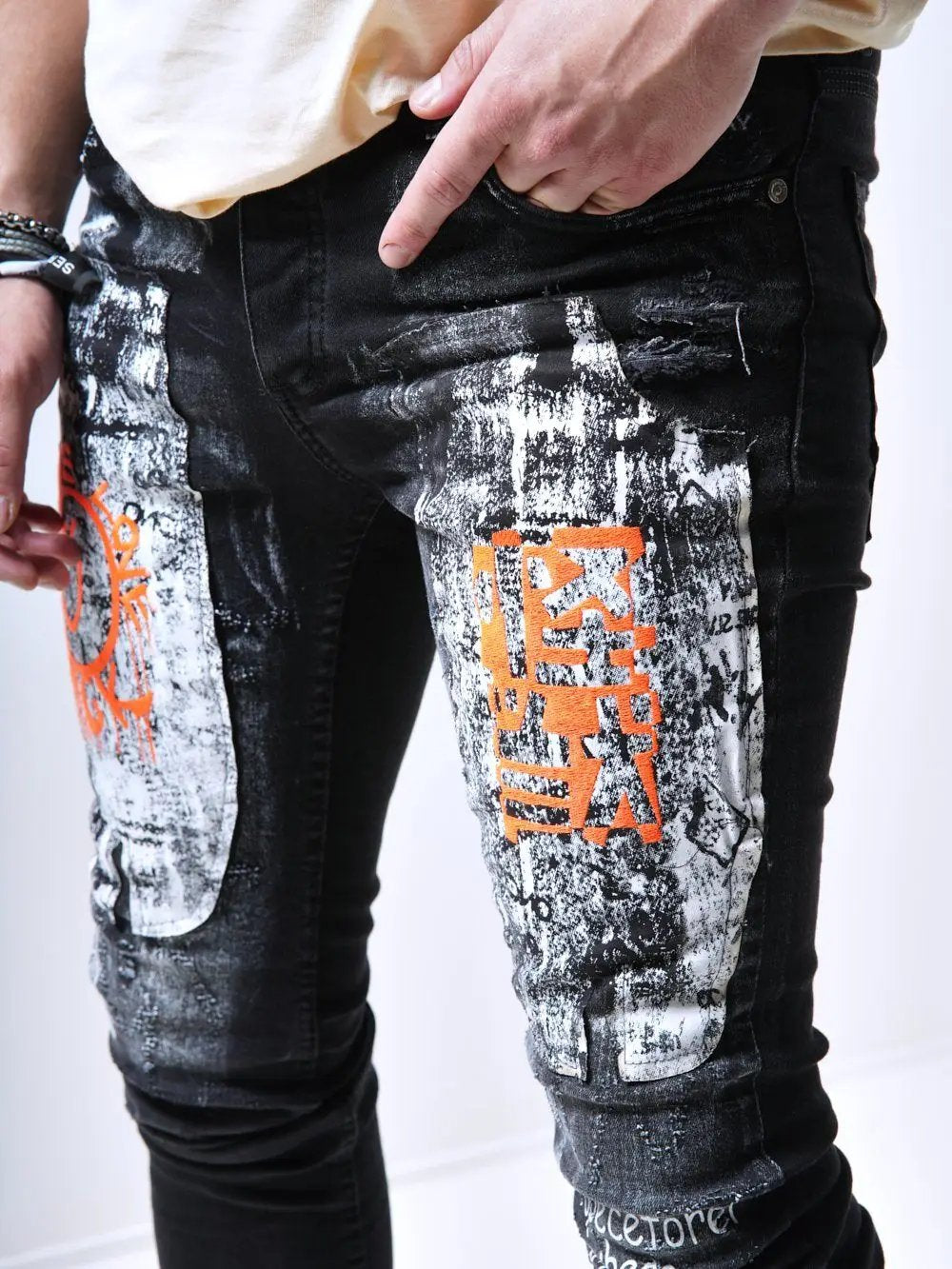 A man wearing a pair of SIXTY SIX jeans with graffiti on them.
