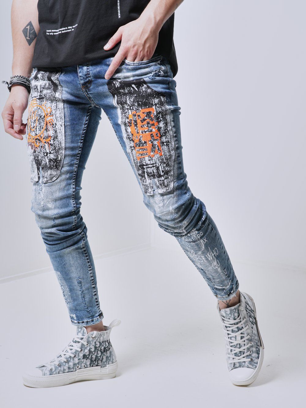 Man wearing the skinny fit jeans with bold graphics called WANDERLUST Streetwear Jeans by SERNES