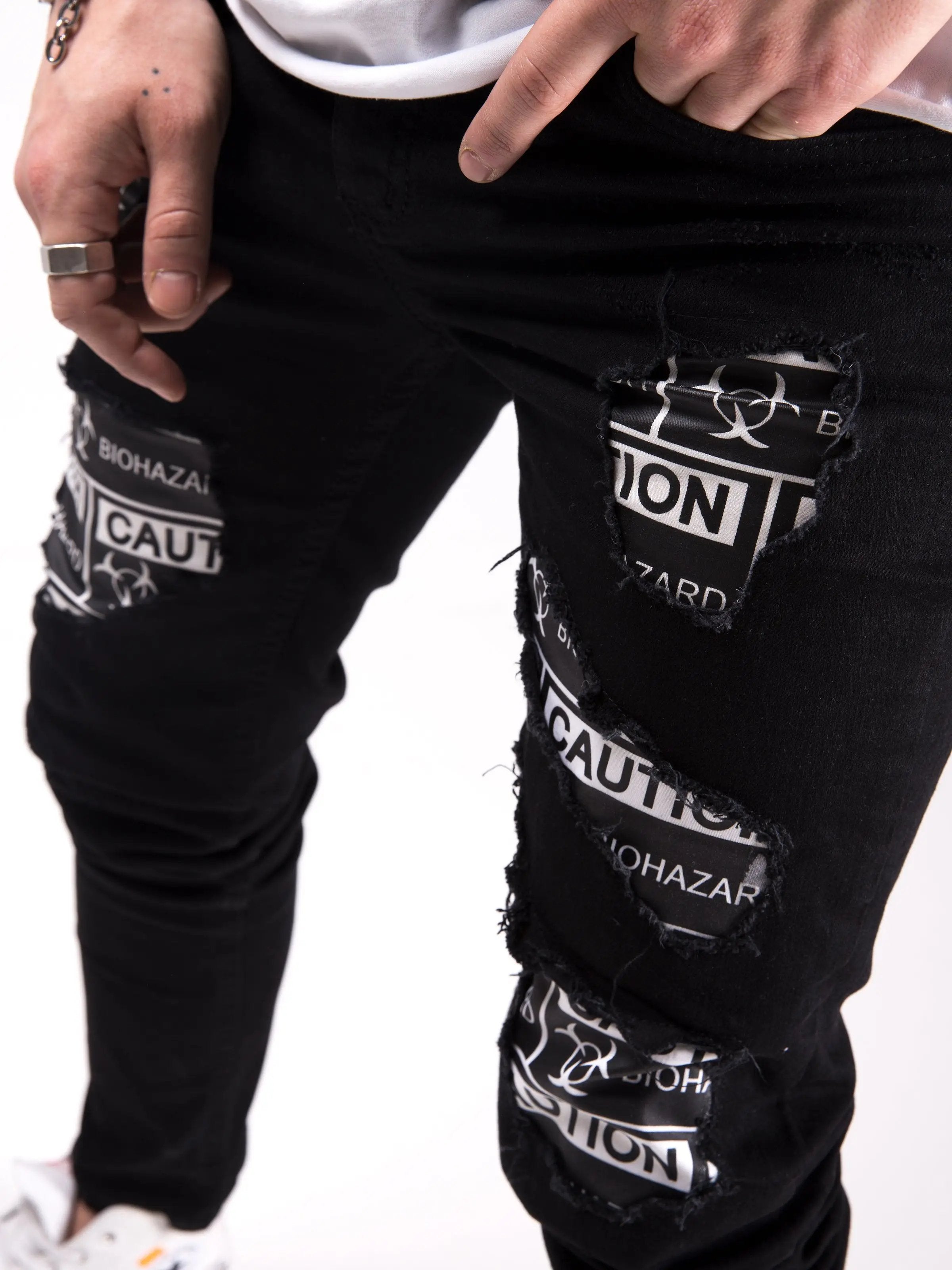 A man wearing a pair of BLACKOUT BIOHAZARD jeans with a message on them.