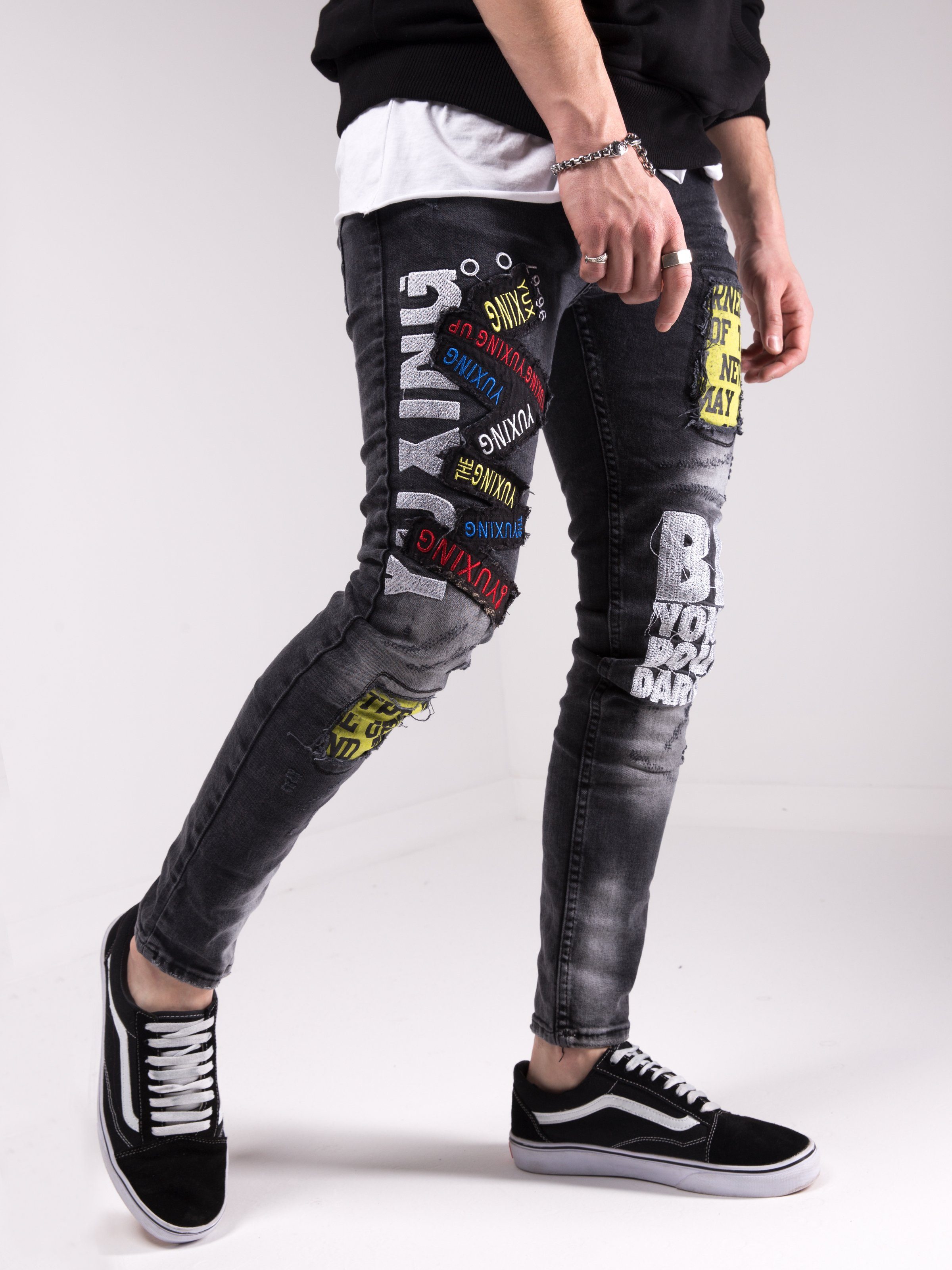 A man wearing a pair of SAVAGE SECRET jeans with graffiti on them.