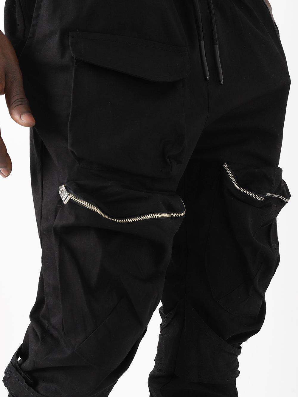 A man wearing black MEREEN JOGGERS with zippers.