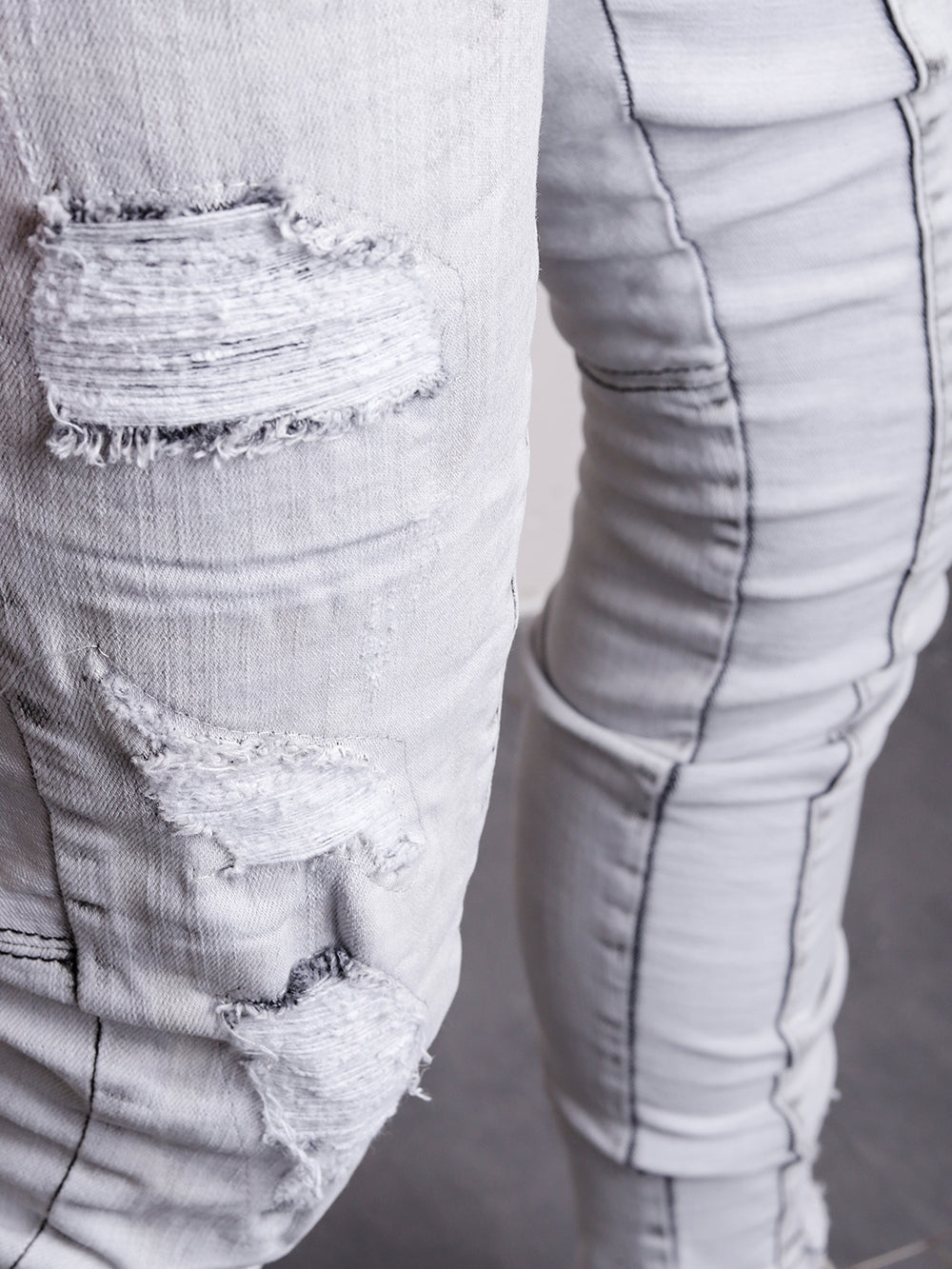 A close up of a person wearing CLOUD 9 distressed denim jeans.