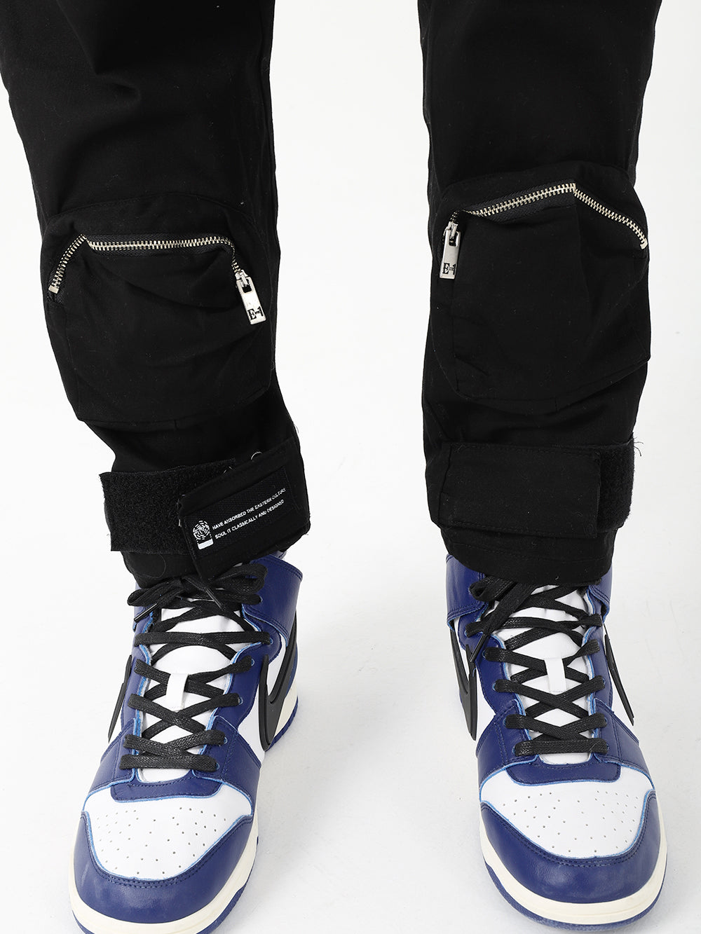 A pair of black and white RAIDER JOGGERS with zippers on them.