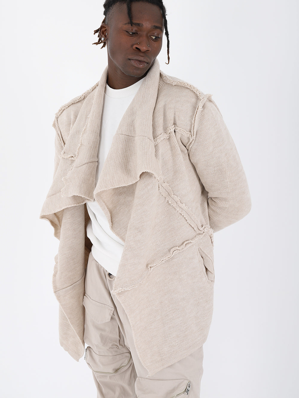 A man wearing an ASYMMETRIC SHORT CARDIGAN // IVORY jacket and pants with a true to size fit.