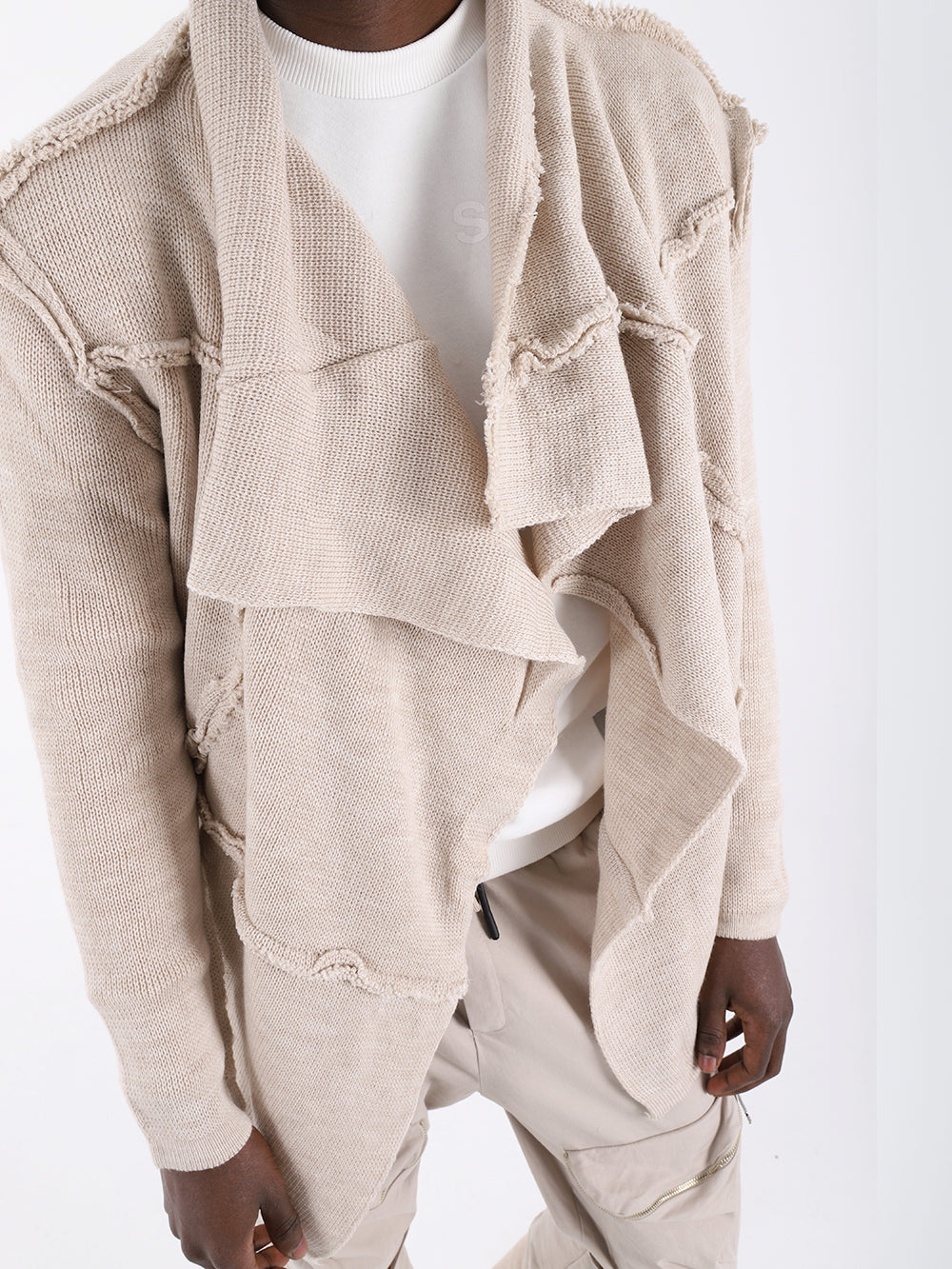 A man wearing the ASYMMETRIC SHORT CARDIGAN // IVORY with a true-to-size fit and khaki pants.