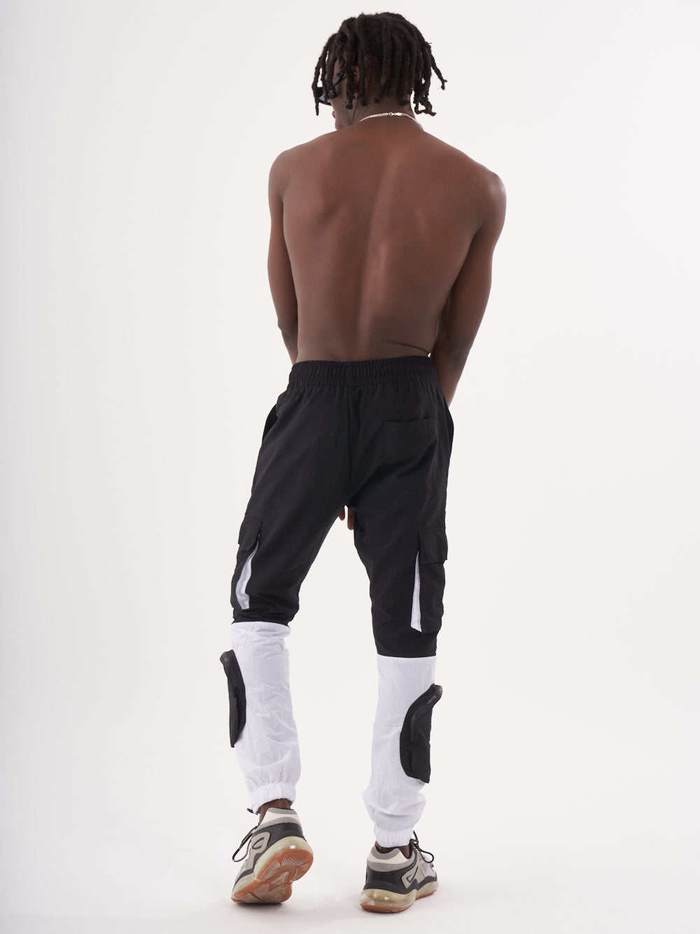 The back of a man wearing RENEGADE | BLACK track pants.