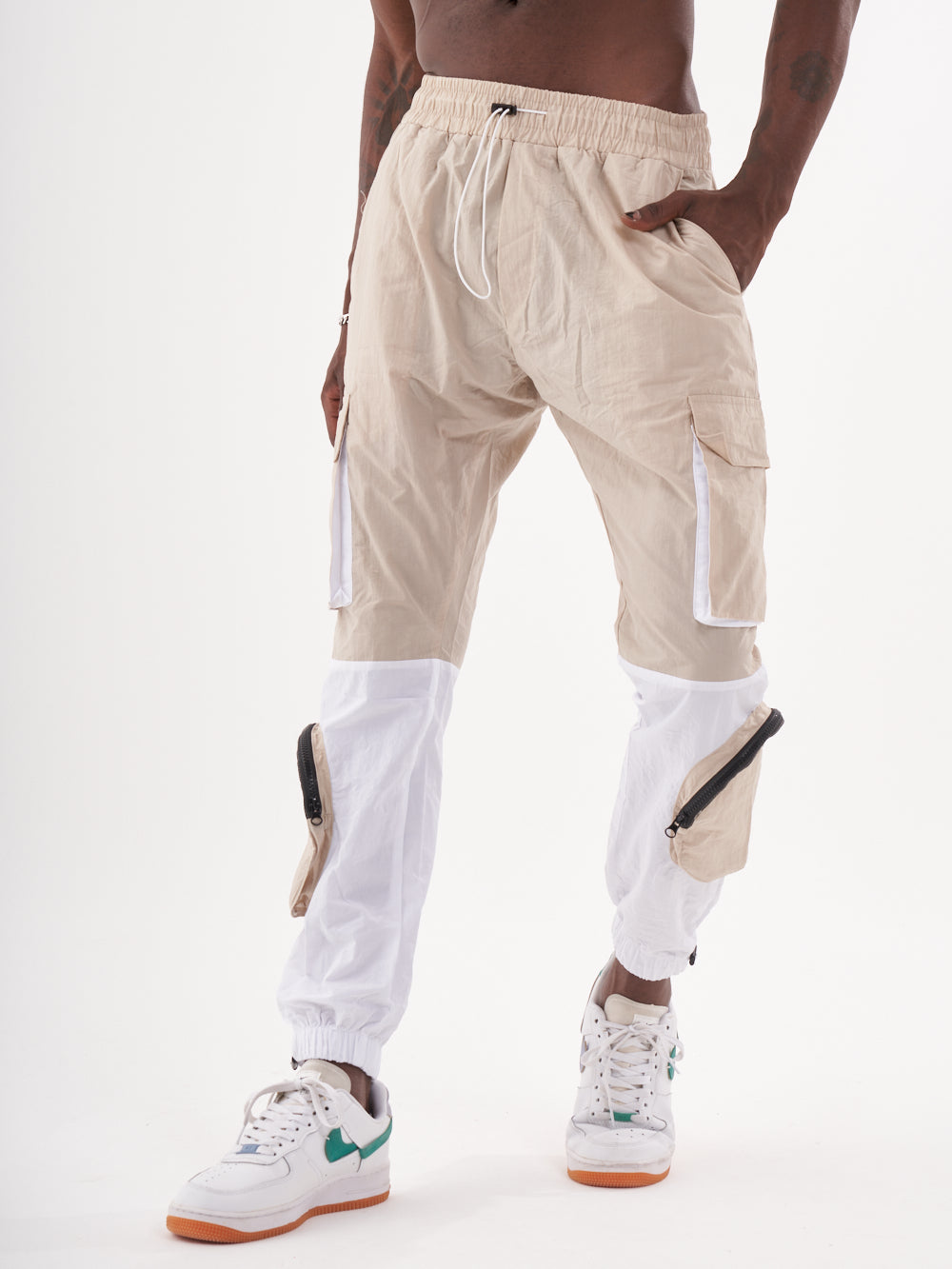 A man wearing RENEGADE | BEIGE cargo pants and white sneakers.