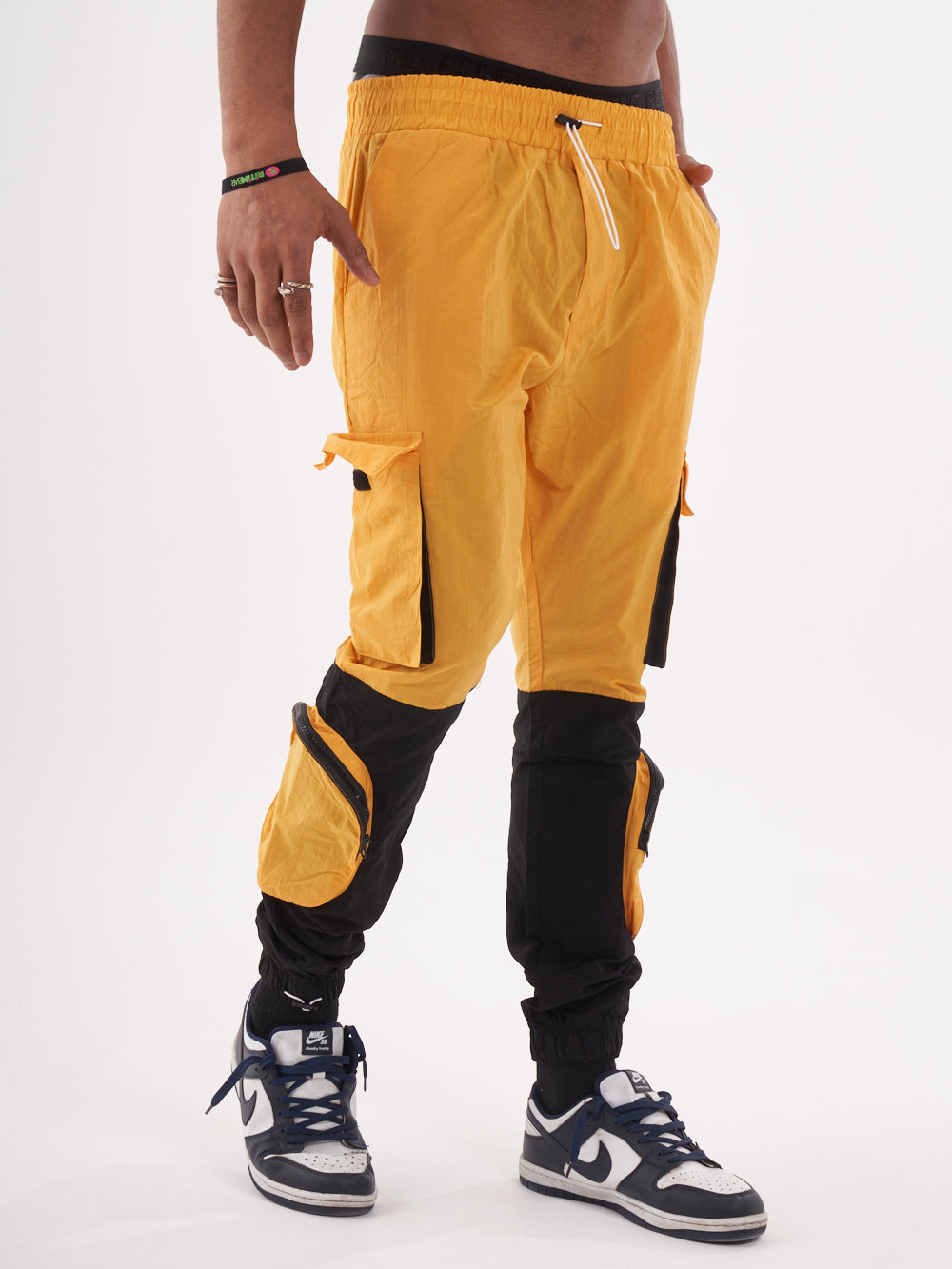 A man wearing Renegade | Yellow cargo pants and black sneakers.