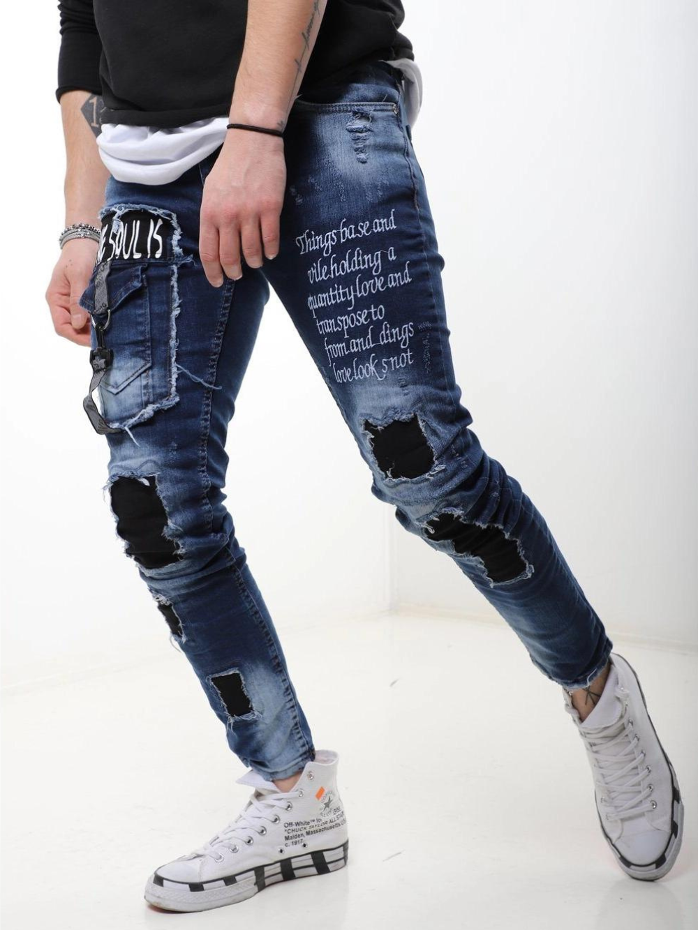 A man wearing ripped jeans and a BLUE SOUL t - shirt.