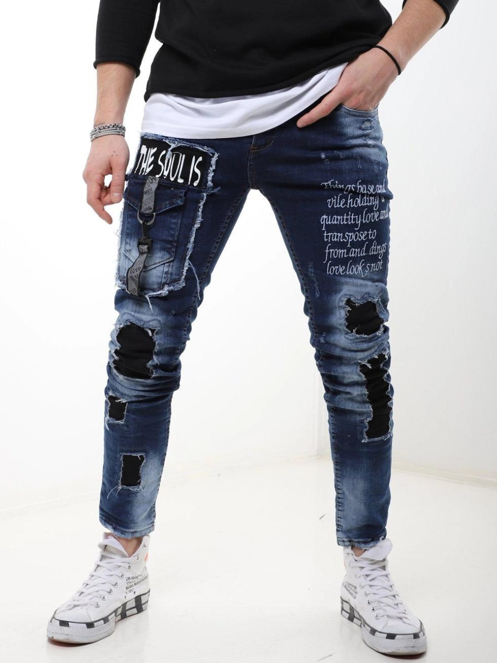 A man wearing ripped jeans and a Blue Soul t - shirt.