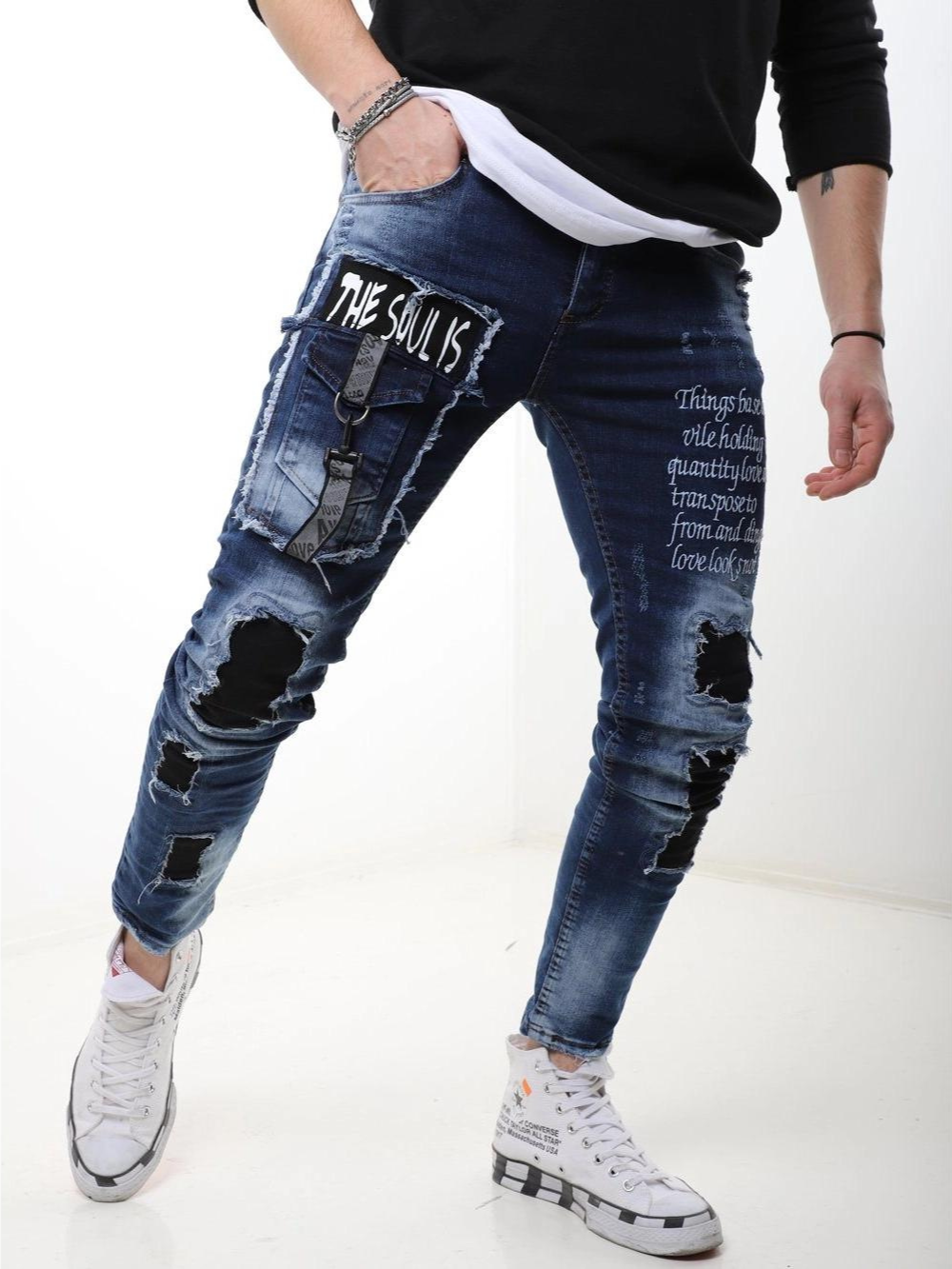A man wearing ripped jeans and a white BLUE SOUL t - shirt.