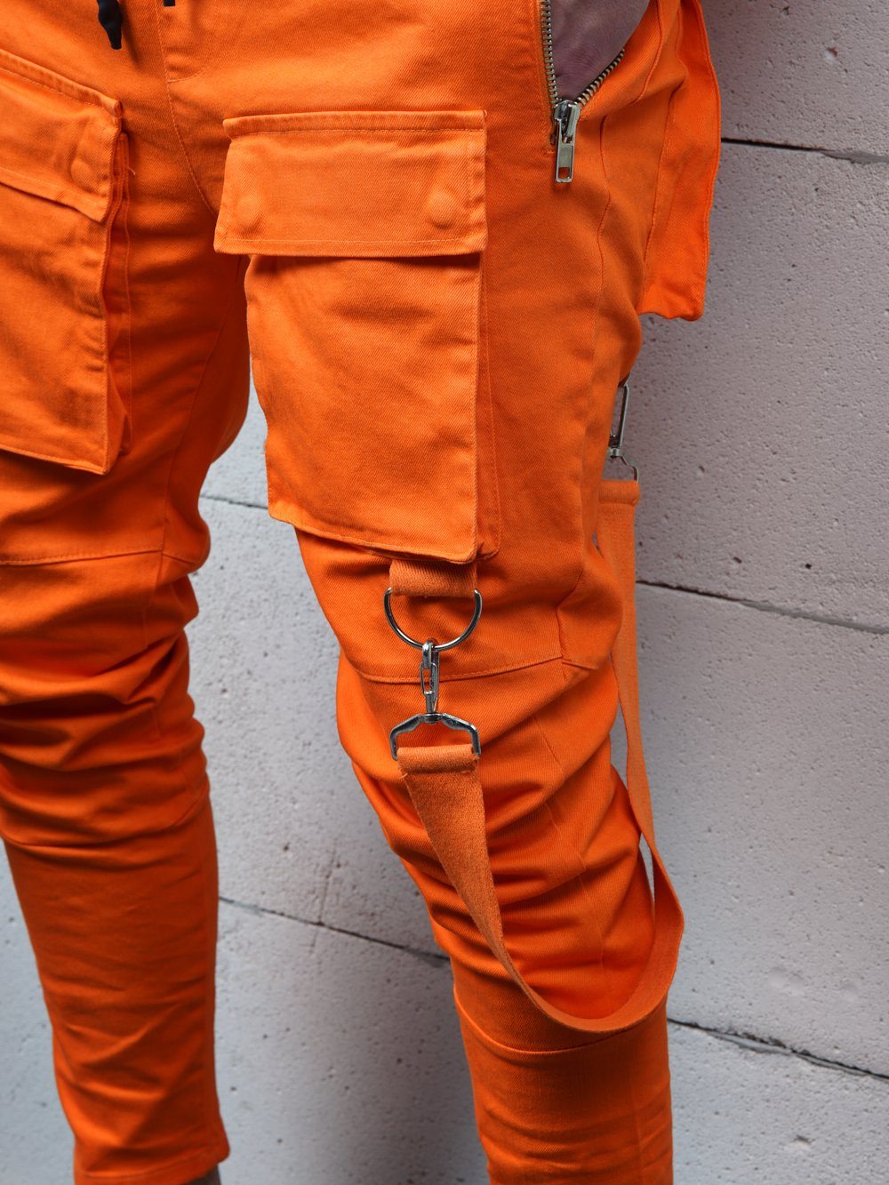 A man wearing ORANGE BRONX cargo pants with straps.