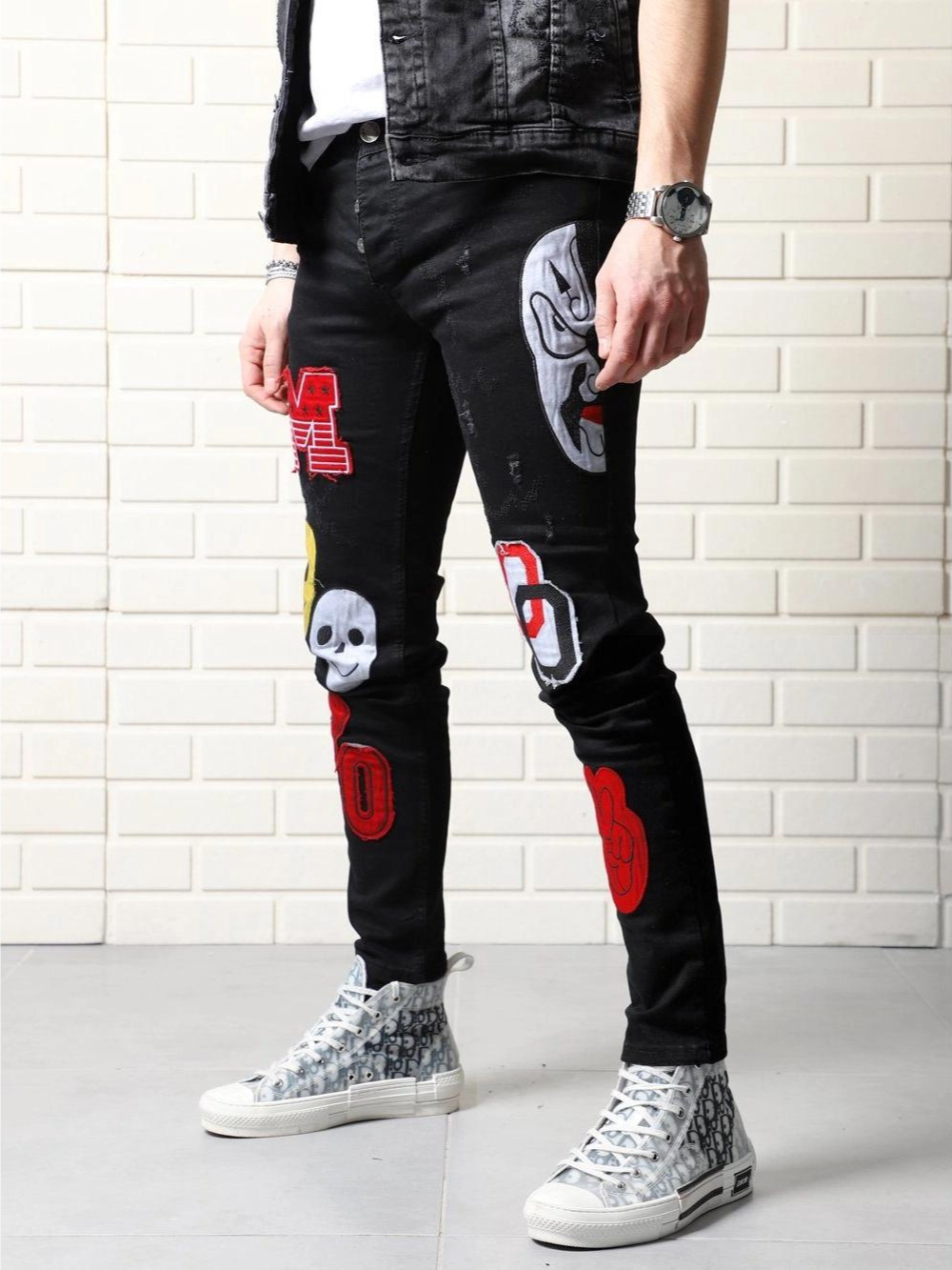 A man wearing a pair of black jeans with a CLOWN CAR patch on them.