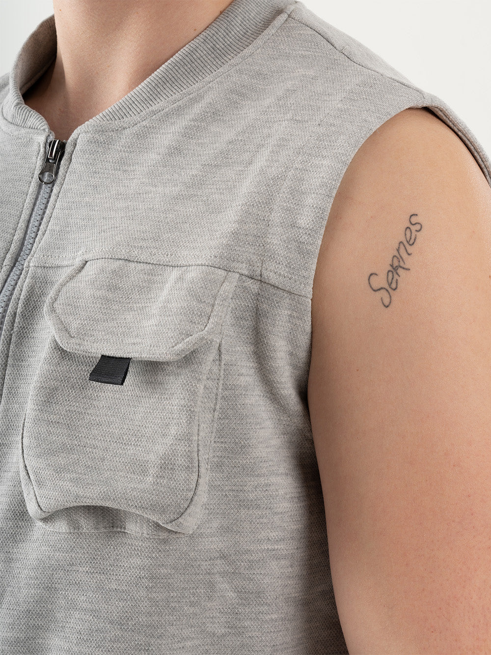 A man wearing a FREESPIRIT VEST with cargo pockets and a tattoo on his arm.