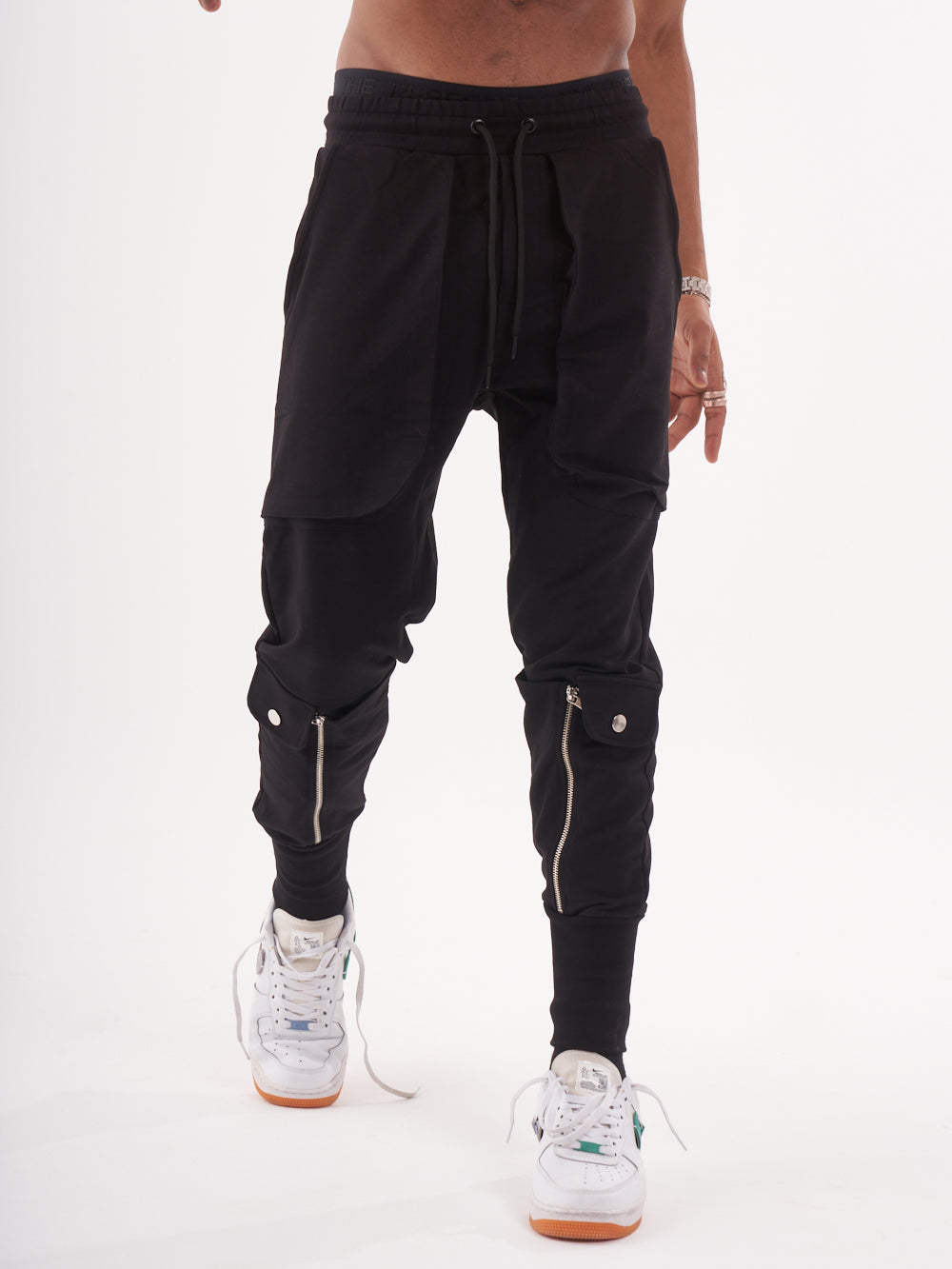 A man wearing GUERRILLA | BLACK joggers with zippers.