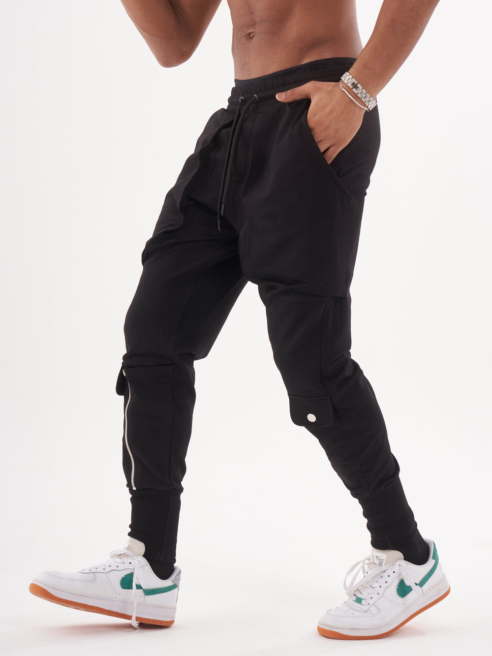 A man in GUERRILLA | BLACK jogging pants posing in front of a white background.