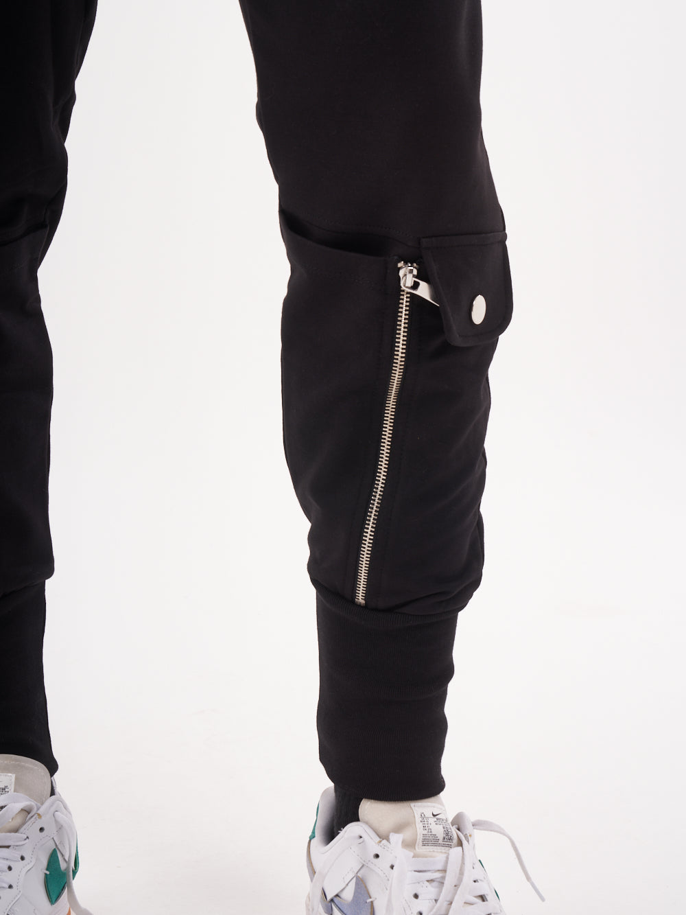 A pair of GUERRILLA | BLACK joggers with zippers on the side.