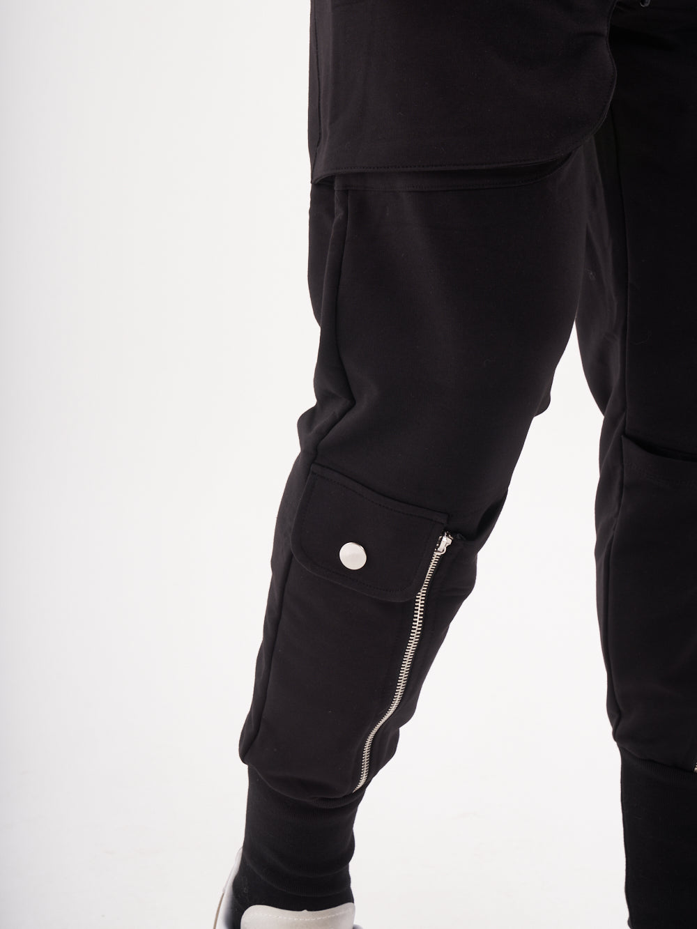 A man wearing a pair of GUERRILLA | BLACK jogging pants with zippers.