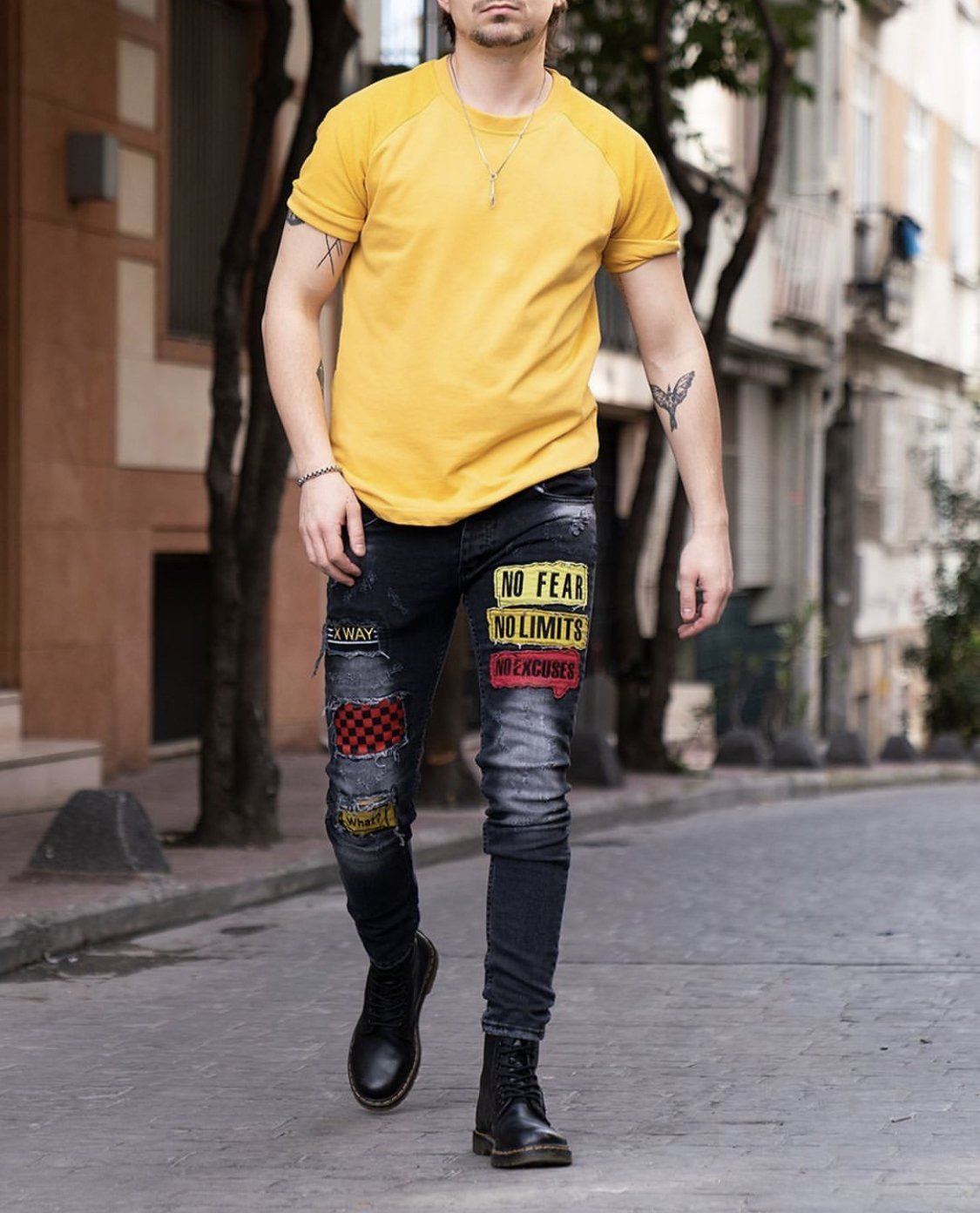 A man in a FEARLESS yellow t-shirt with a skinny fit walking down the street.