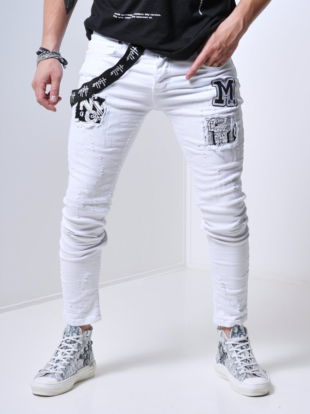 A man sporting MASSIVE skinny fit white jeans in a trendy streetwear style.