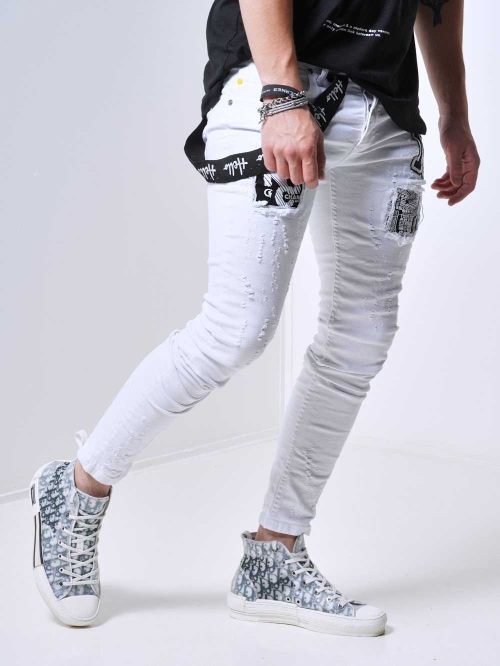 A man wearing MASSIVE skinny fit white jeans and black sneakers.