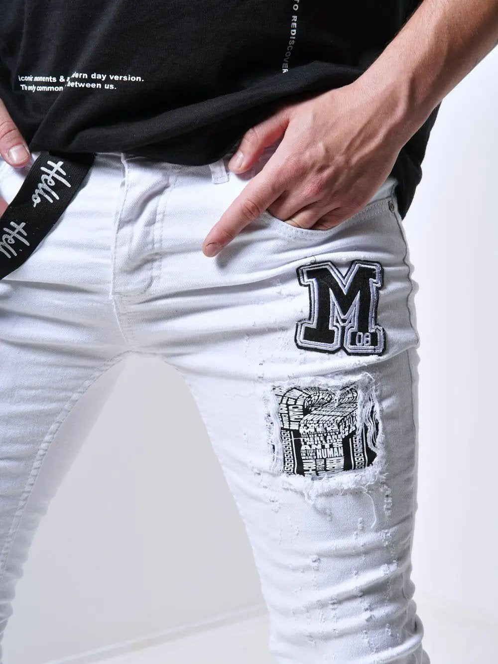 A man in MASSIVE skinny fit white ripped jeans and a black t-shirt showcases his trendy mens streetwear style.