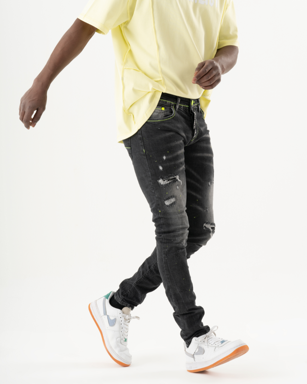 A man wearing INKLING skinny fit black jeans and a yellow t-shirt in mens streetwear style.