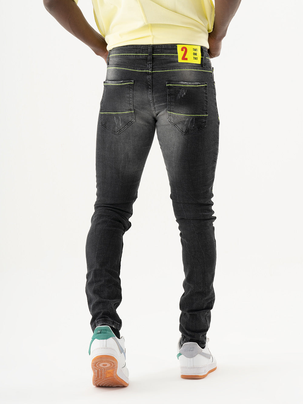 The back of a man wearing INKLING skinny fit black jeans and a yellow t-shirt.