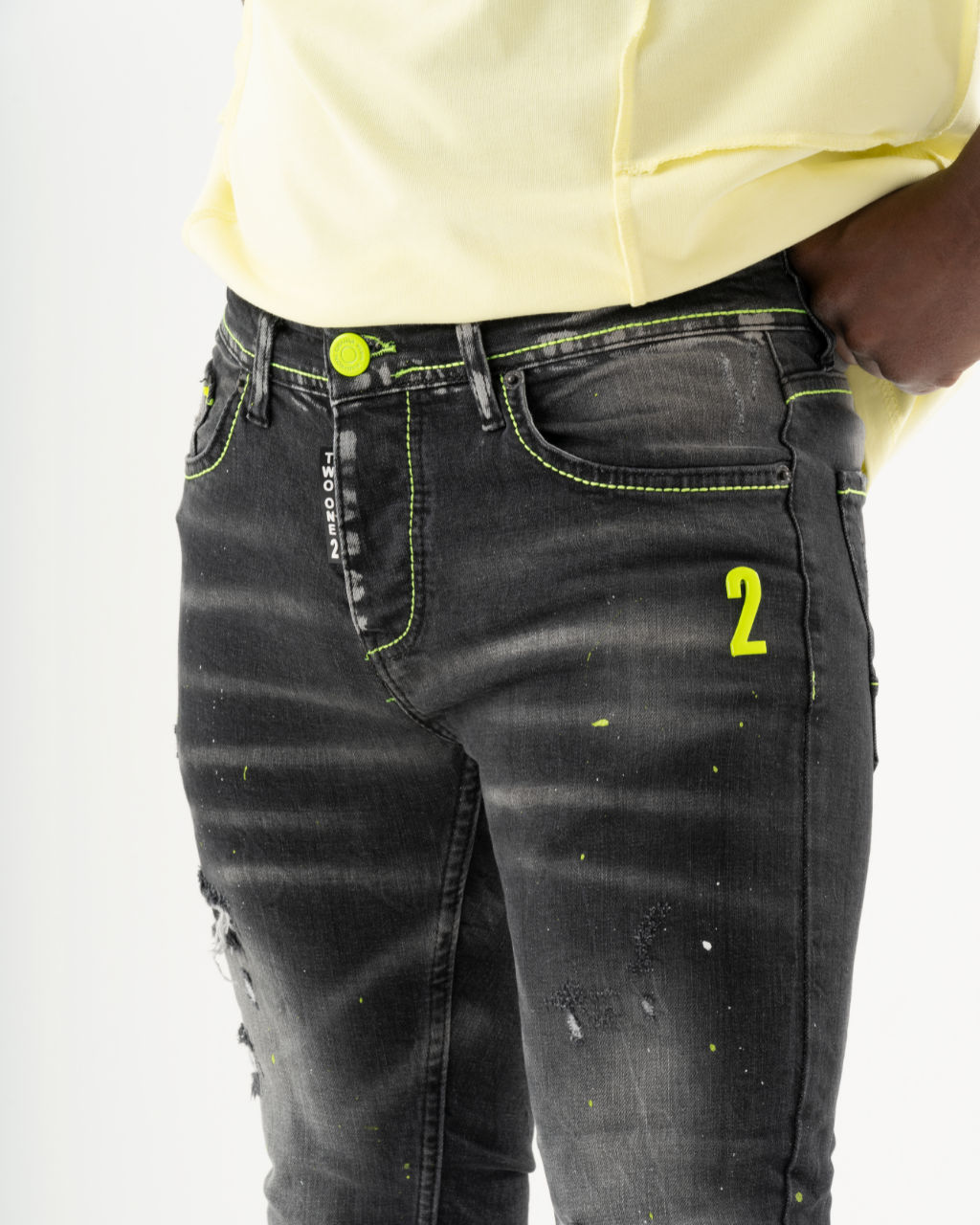 A man is wearing a pair of INKLING skinny fit black jeans with neon paint on them.